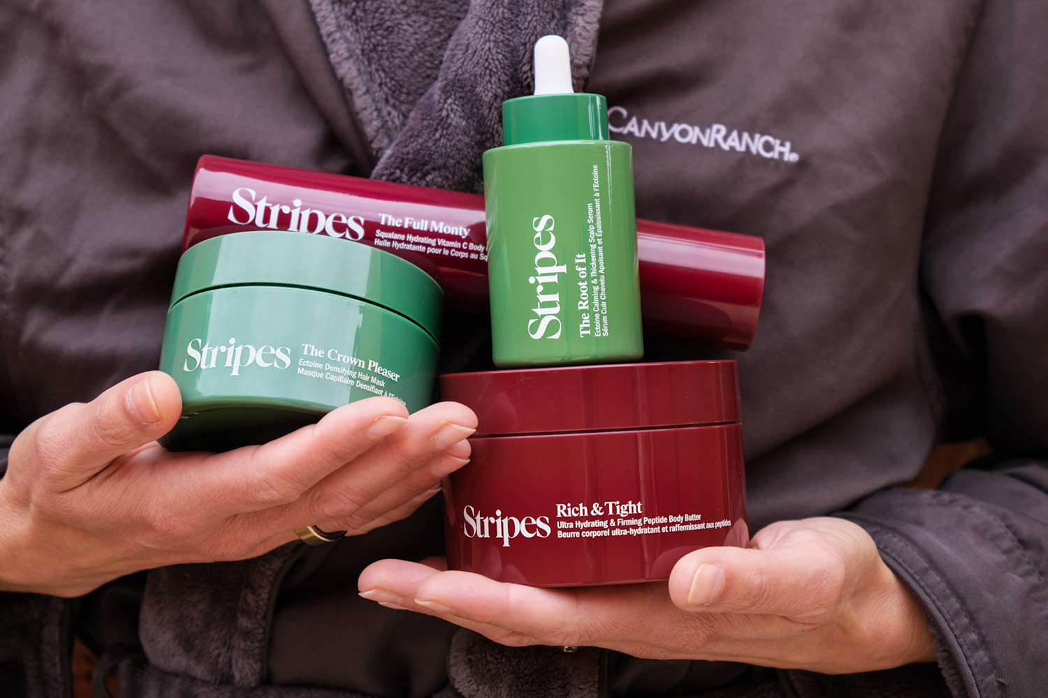 a woman at the canyon ranch spa in a bath robe holding stripes beauty products