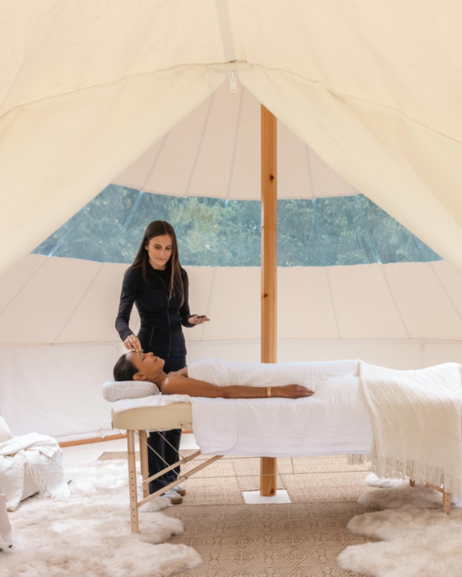 A woman getting a chakra massage in a tent