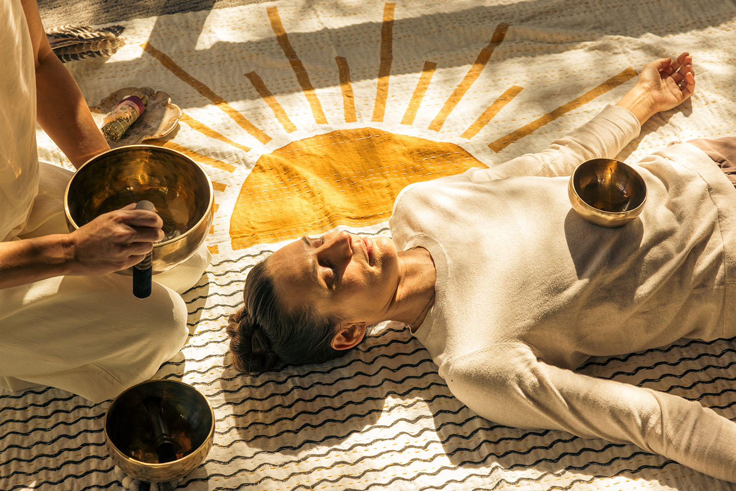 Woman Meditating on Floor Surrounded by Sound Bowls 