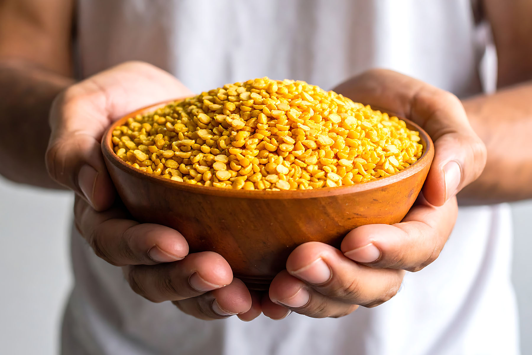 a person holding a bowl of yellow lentils