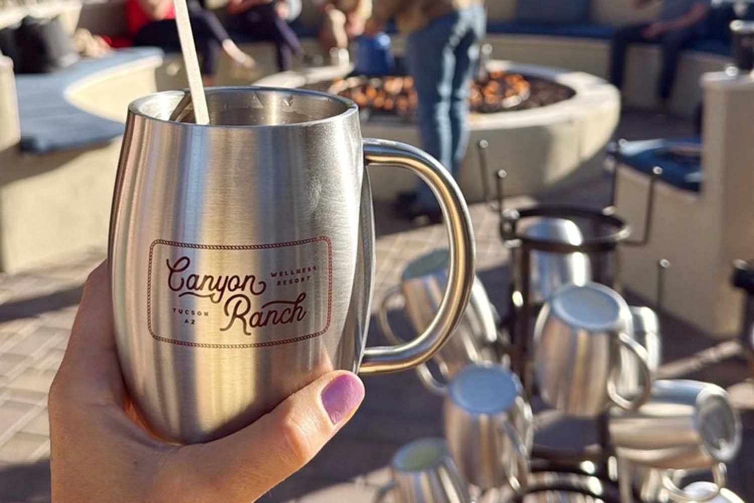 a woman holding a Canyon Ranch mug by the pool at Canyon Ranch Tucson