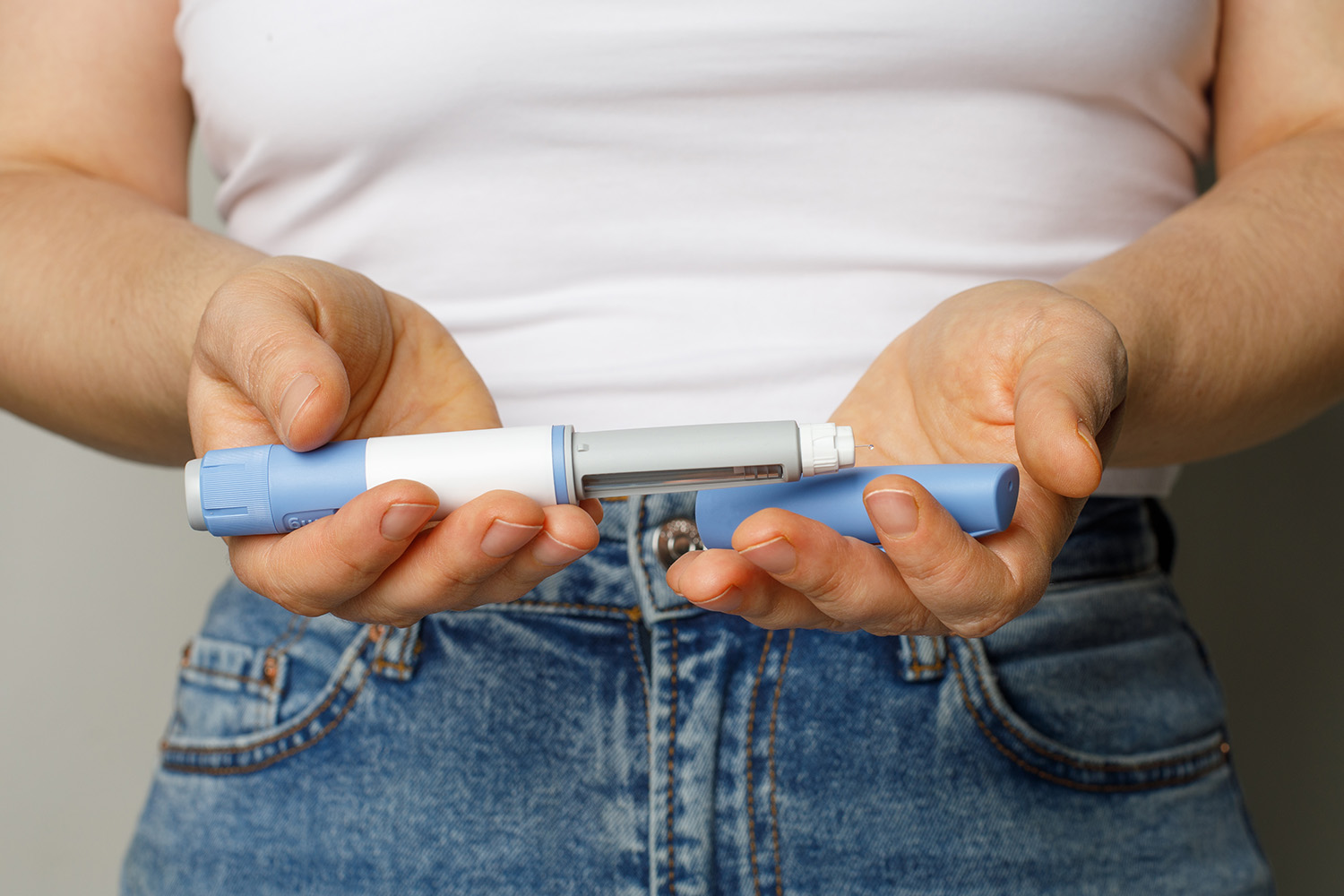 a woman holding a GLP-1 injector