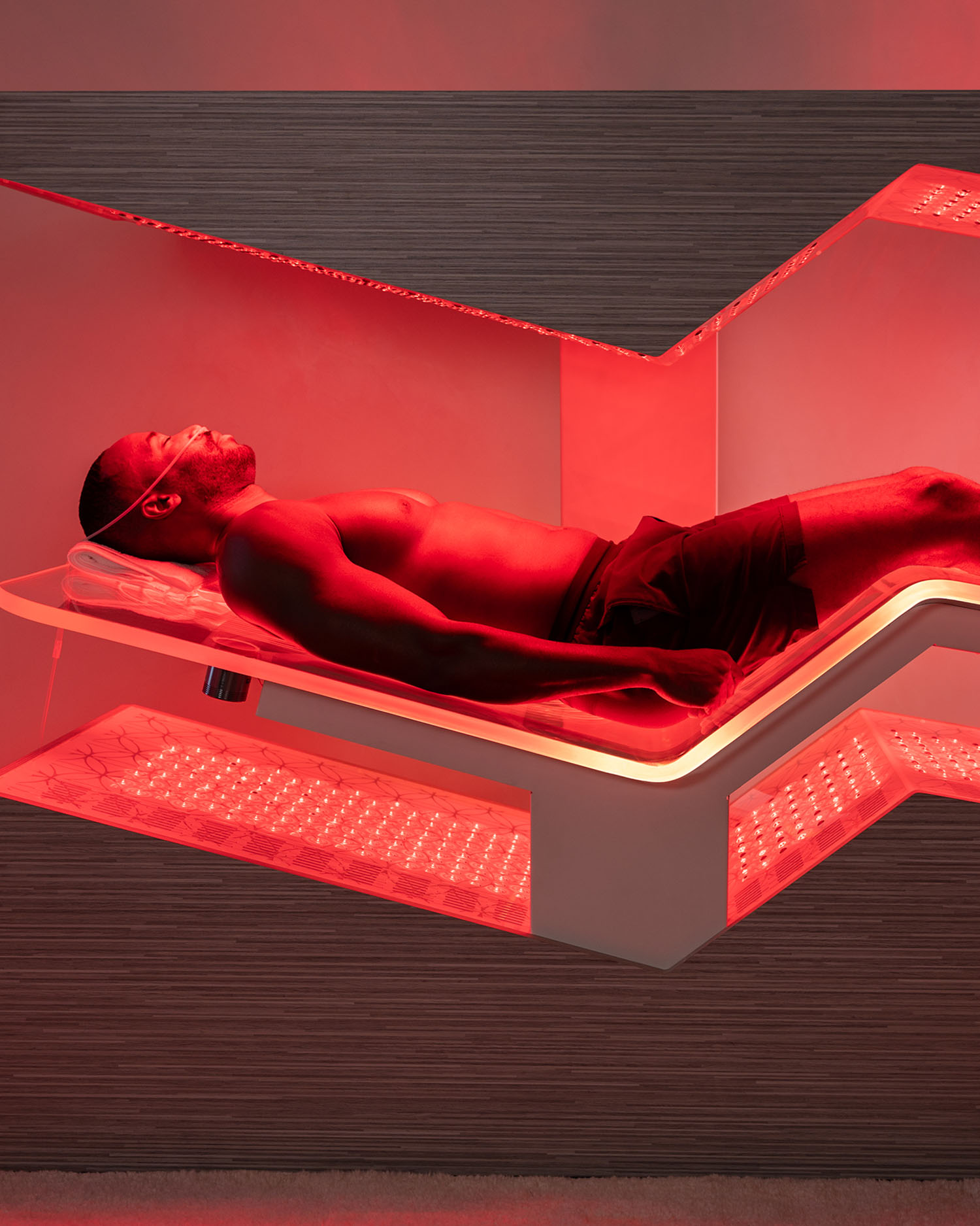 A man laying on a red light therapy bed