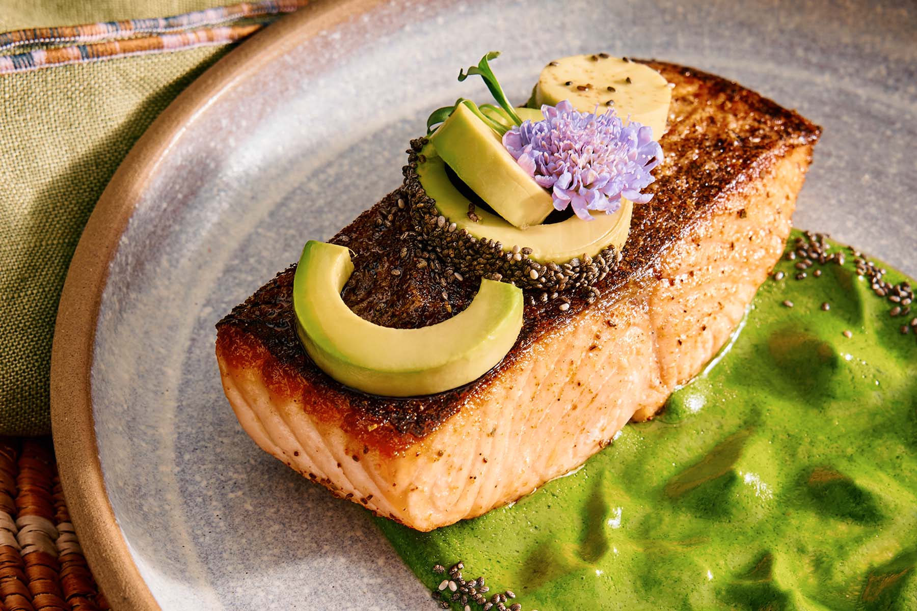 a plate of salmon on an herb dressing