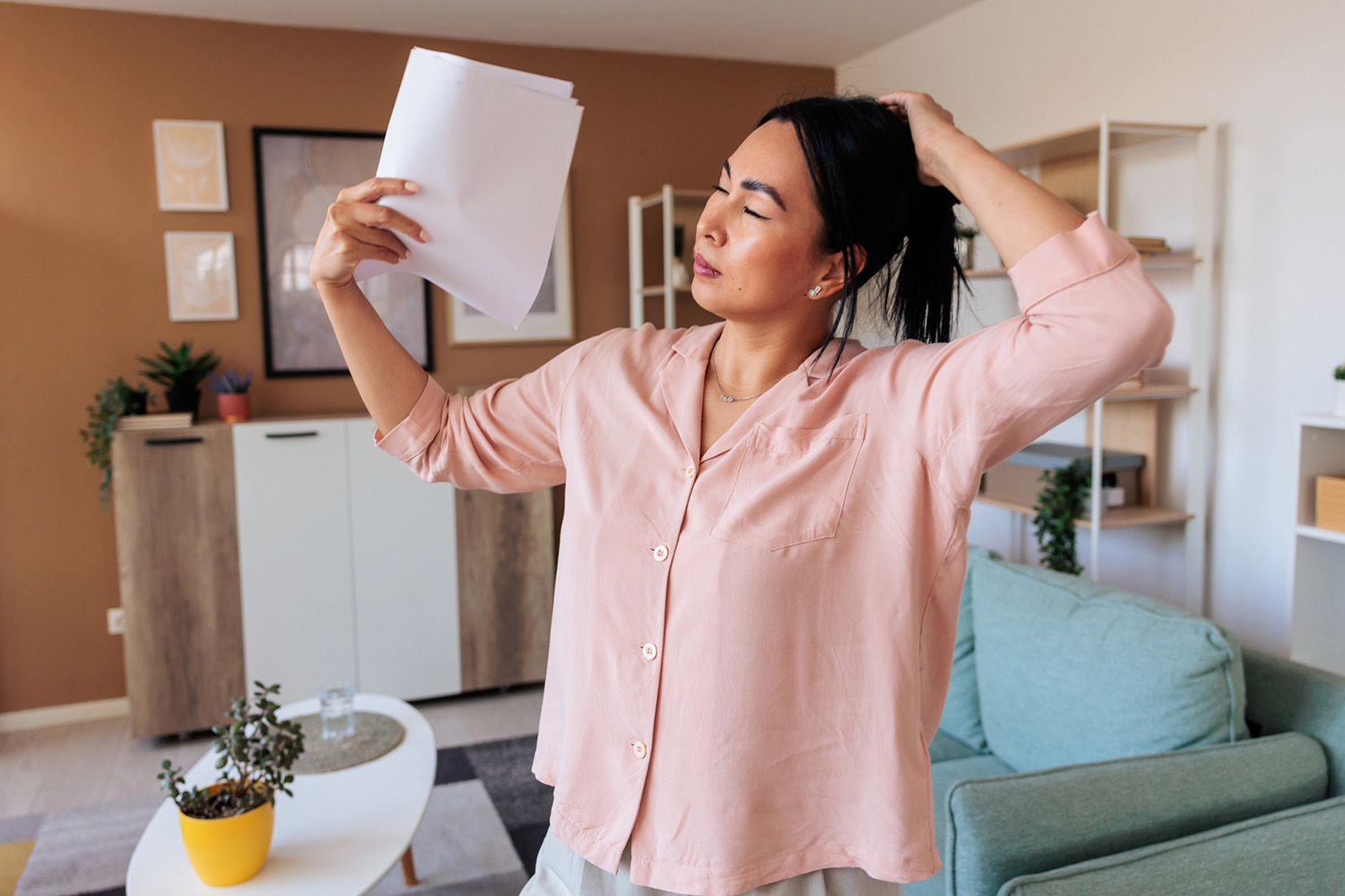 Woman Waving Paper in Her Face Due to Experiencing a Menopause symptom Called Hot Flashes