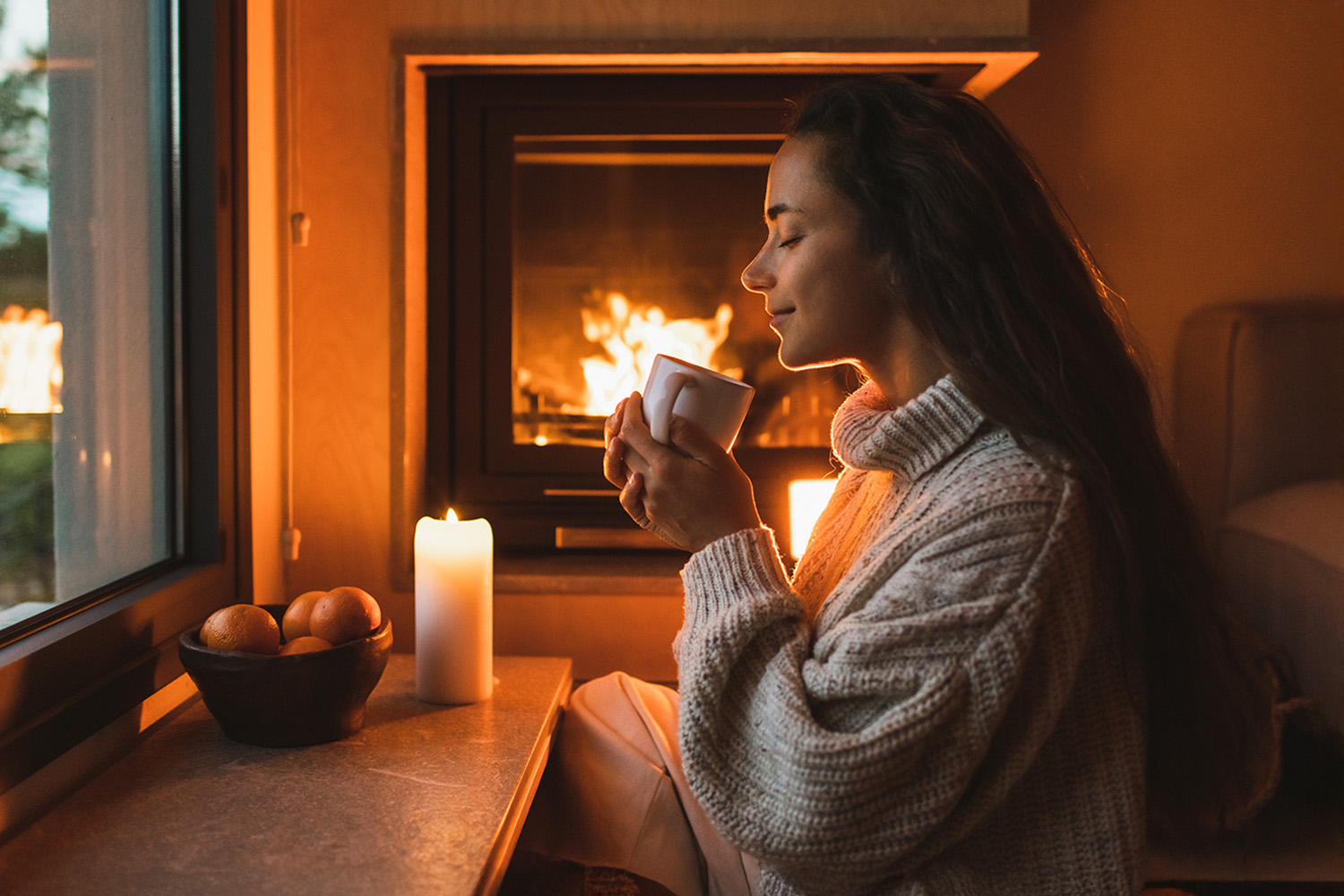 Woman Drinking a Hot Drink in Front of a Fire