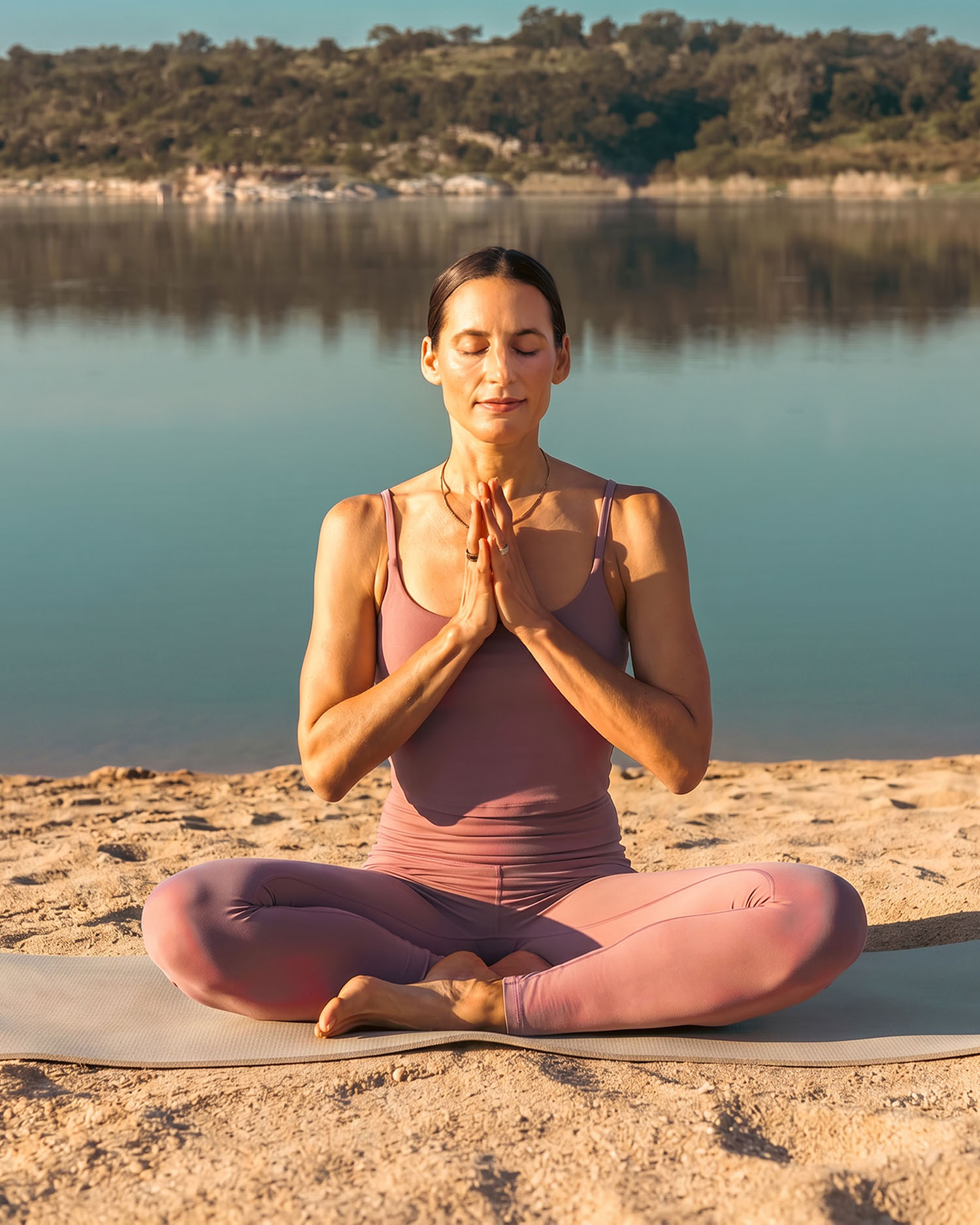 A woman meditating on the beach of Lake Travis