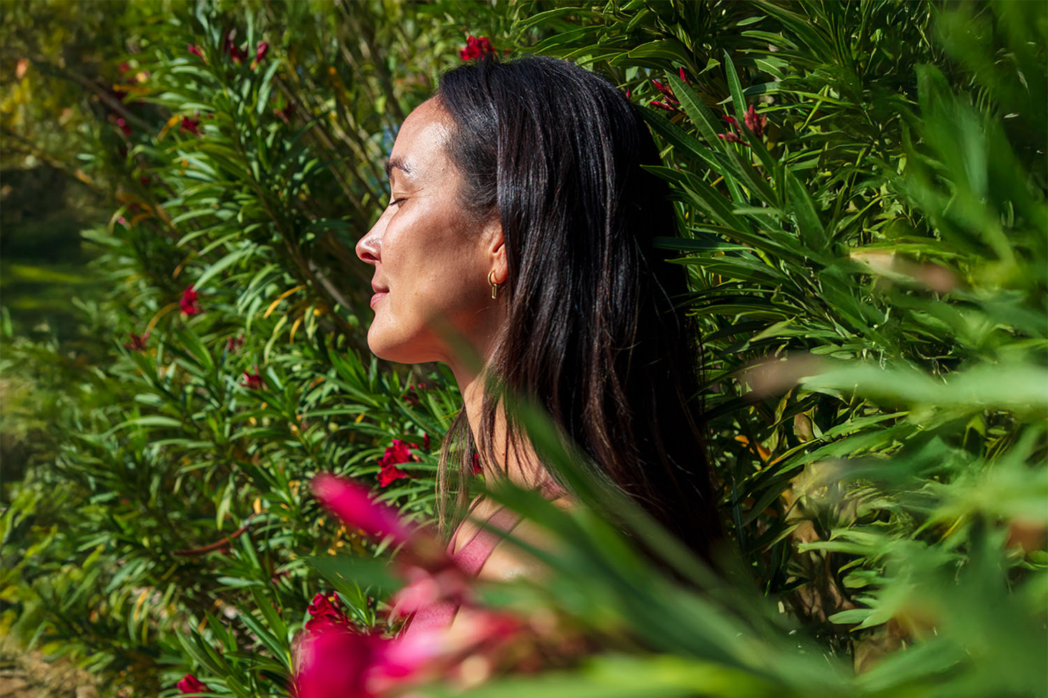 Woman Standing With Closed Eyes Between Green Bushes and Pink Flowers 