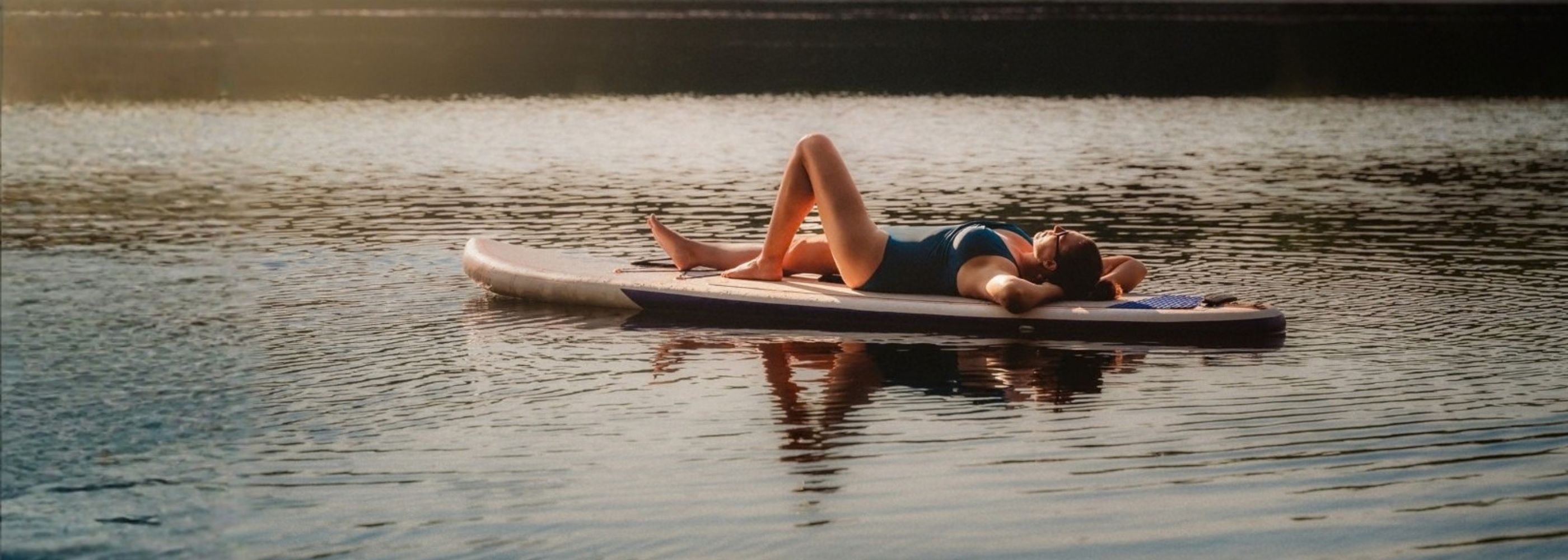 A woman on a lake on a paddle bard. 