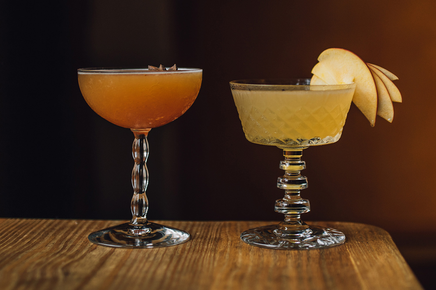 two glasses of seasonal fall colored cocktails and mocktails