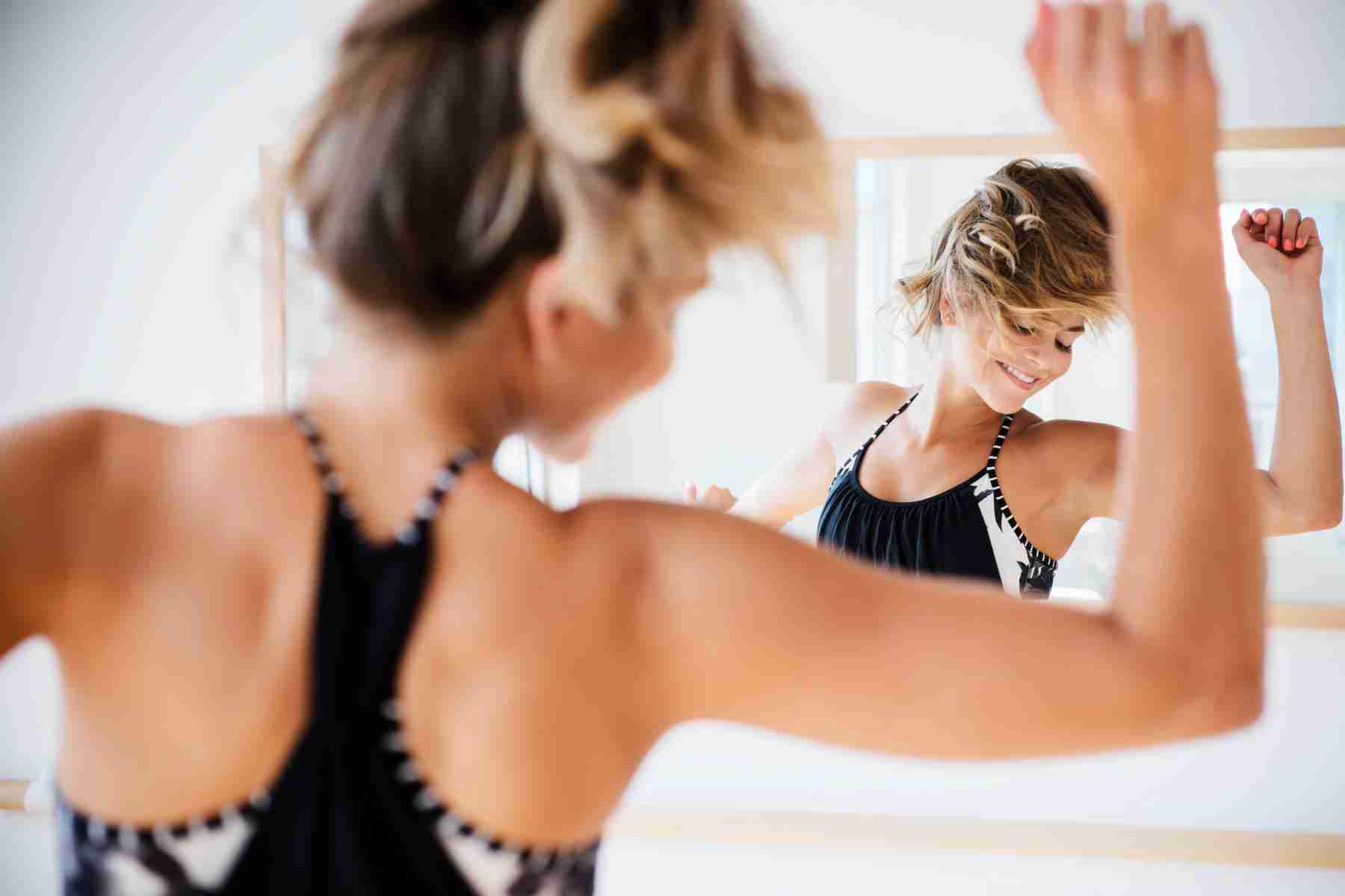 A woman dancing in front of a mirror.