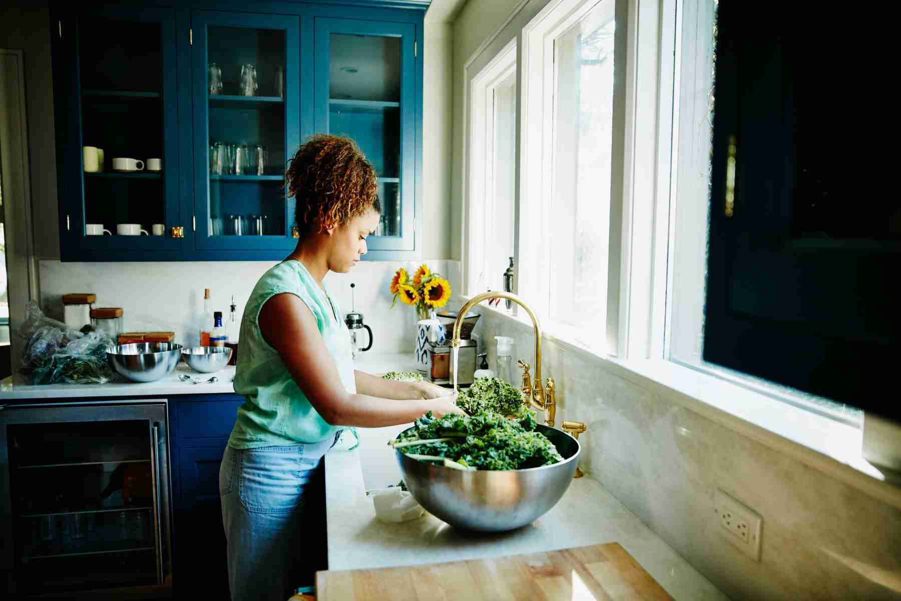 woman washing kale in sink