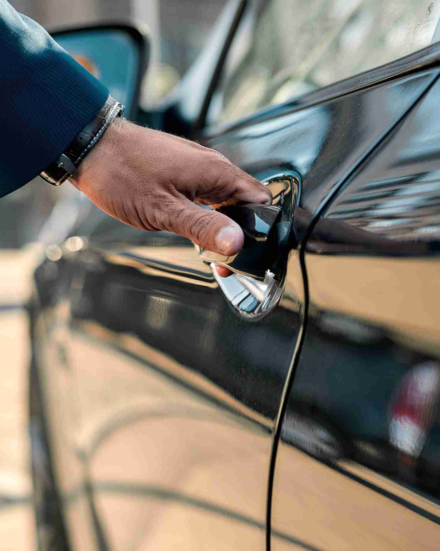 A man opening a black towncar door