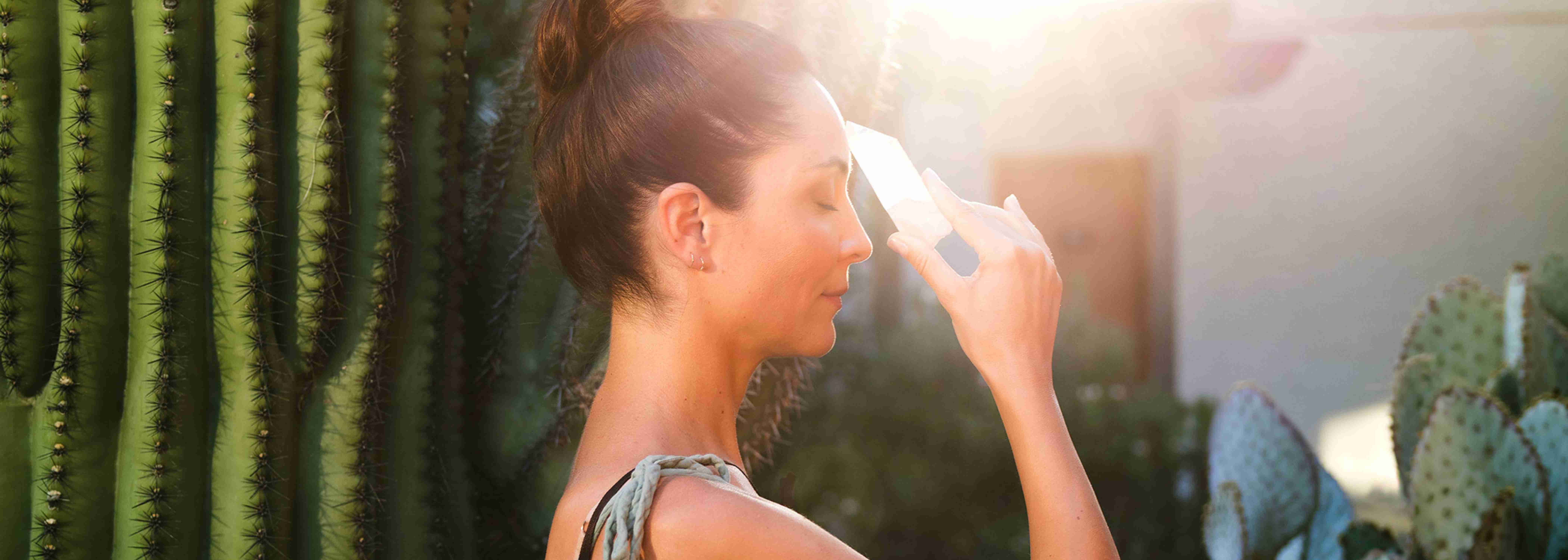 A woman holding a crystal to her forehead