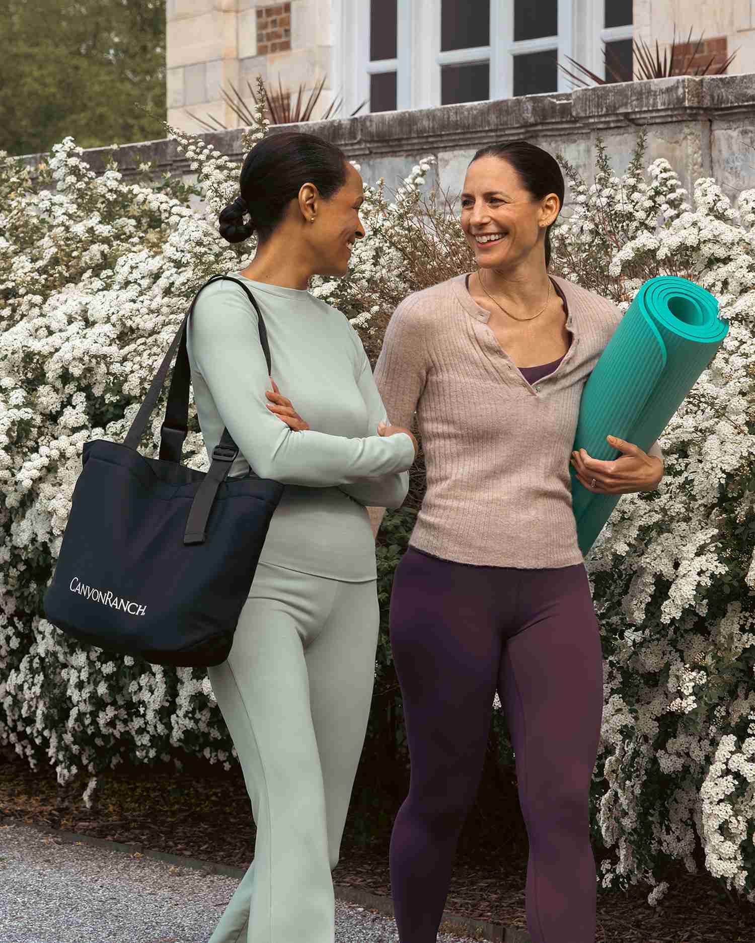 two women walking along a path of flowers