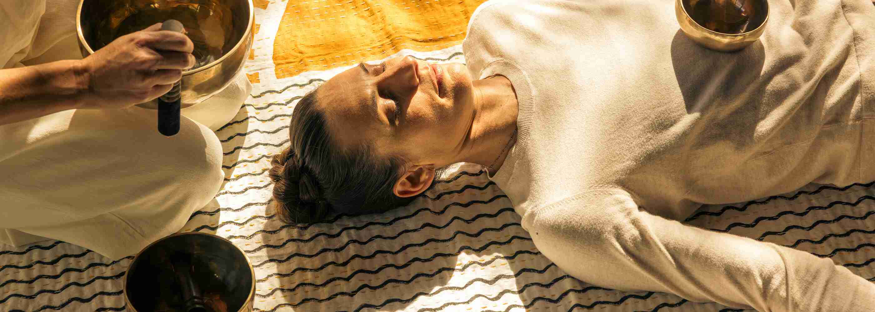 A woman sitting on a wall at sunrise meditating