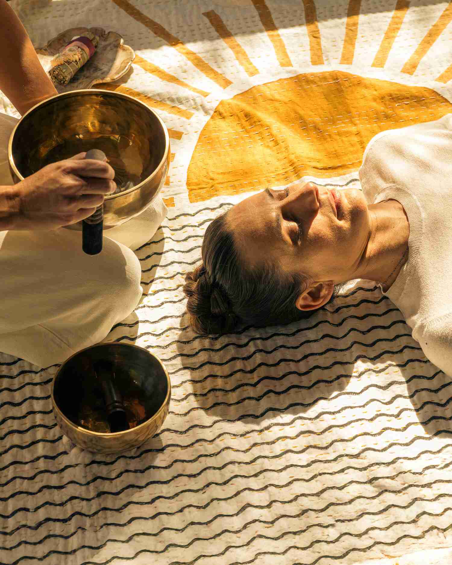 A woman sitting on a wall at sunrise meditating