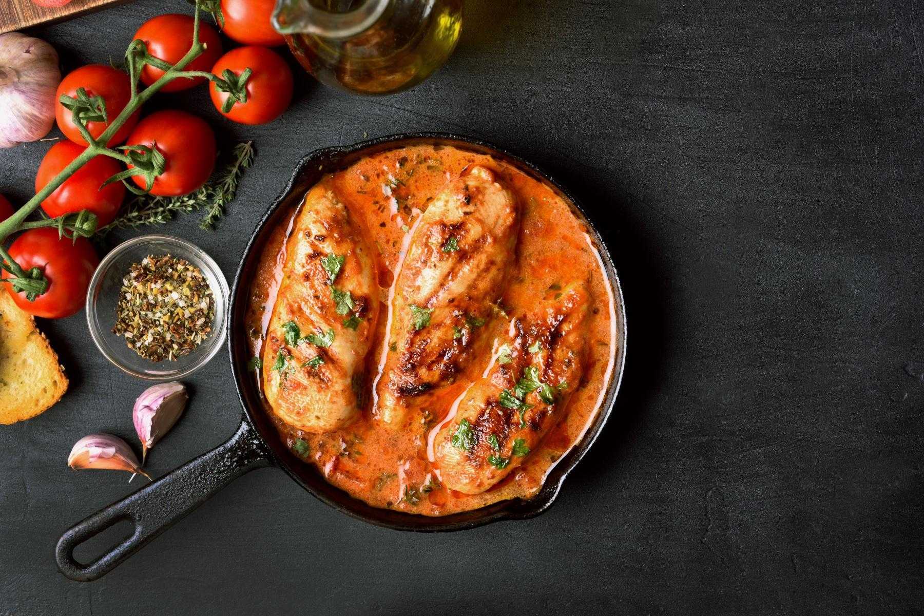 Overhead view of a plate of sautéed Mediterranean chicken with tomato demi-glace.
