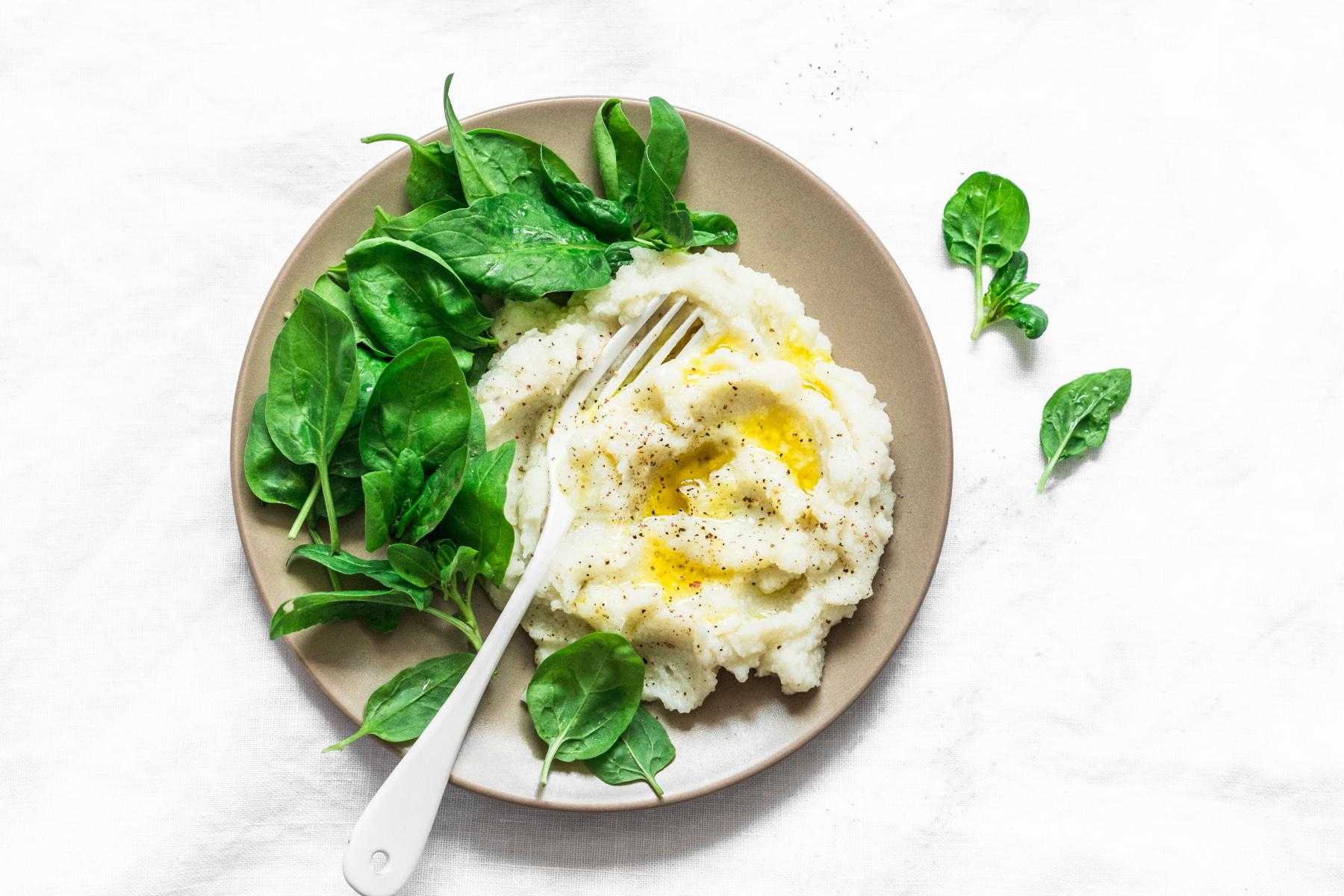 Overhead view of mashed cauliflower on plate with spinach.