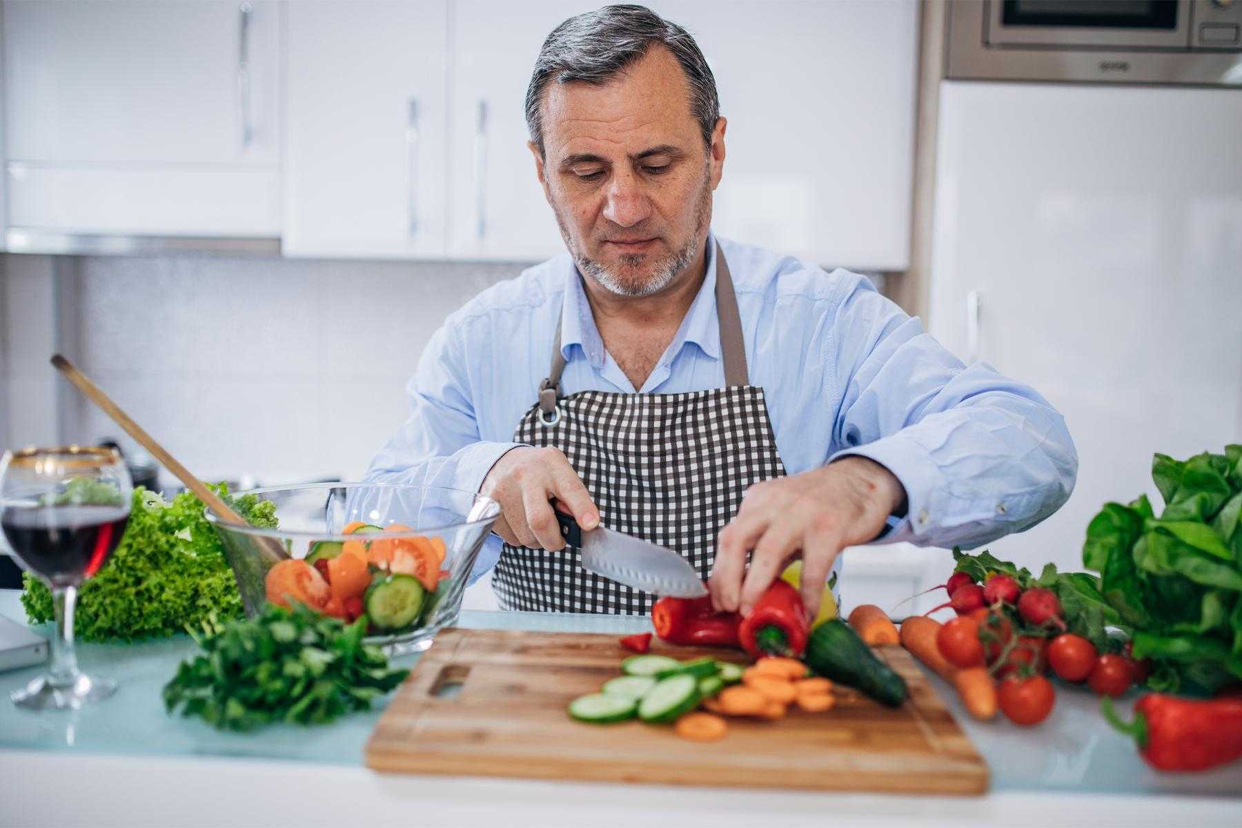 Close-up image of man chopping vegetables.