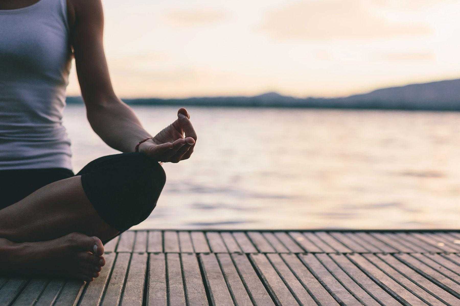 Woman meditating on dock.