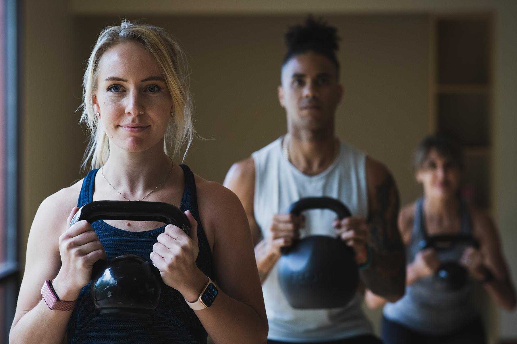 Group of men and women working out with kettlebells.
