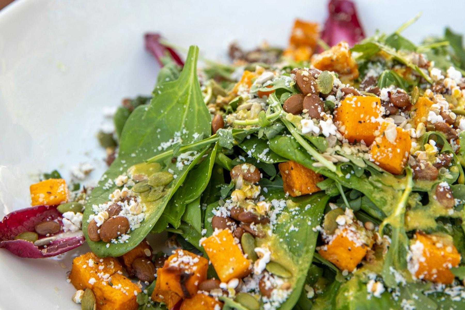 Close-up of salad with spinach, butternut squash, and cheese.