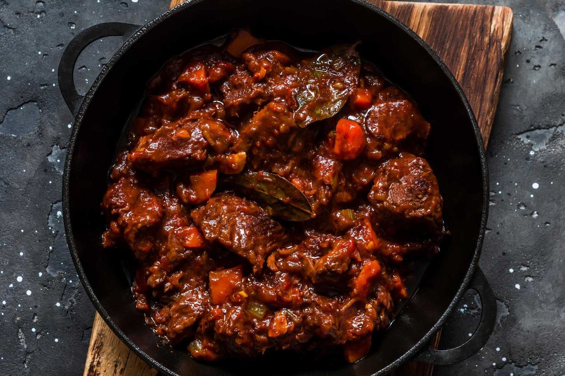Overhead view of seared beef in pan with tomato.