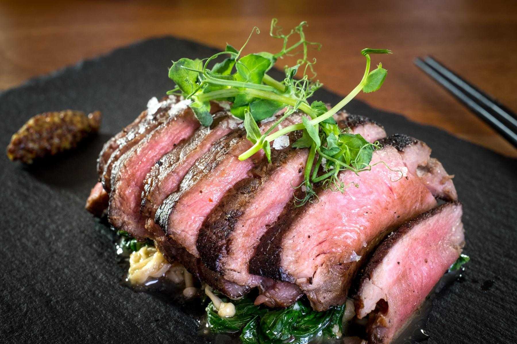 Sliced London broil on black plate.