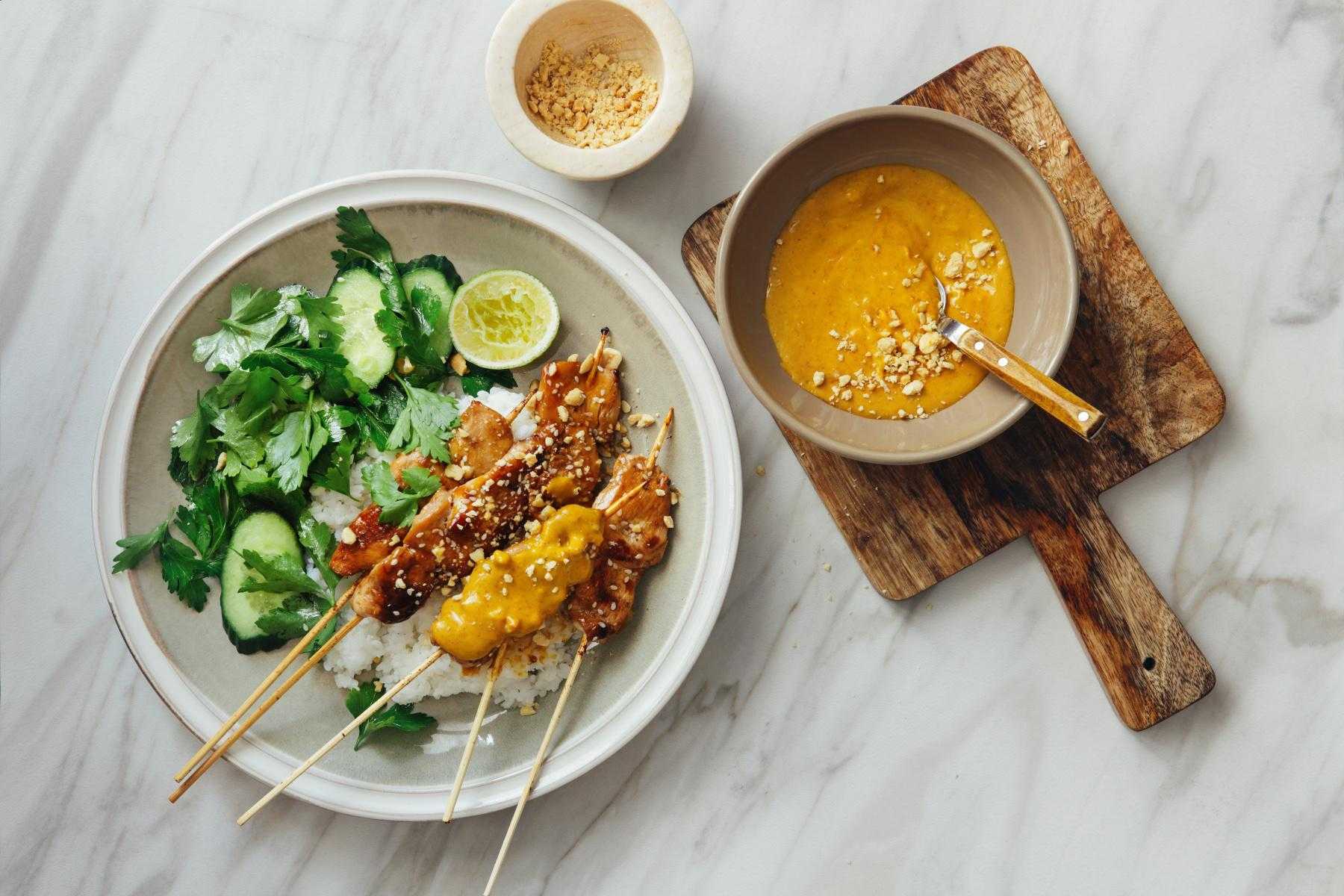 Overhead view of Thai peanut sauce and chicken and veggies on plate.