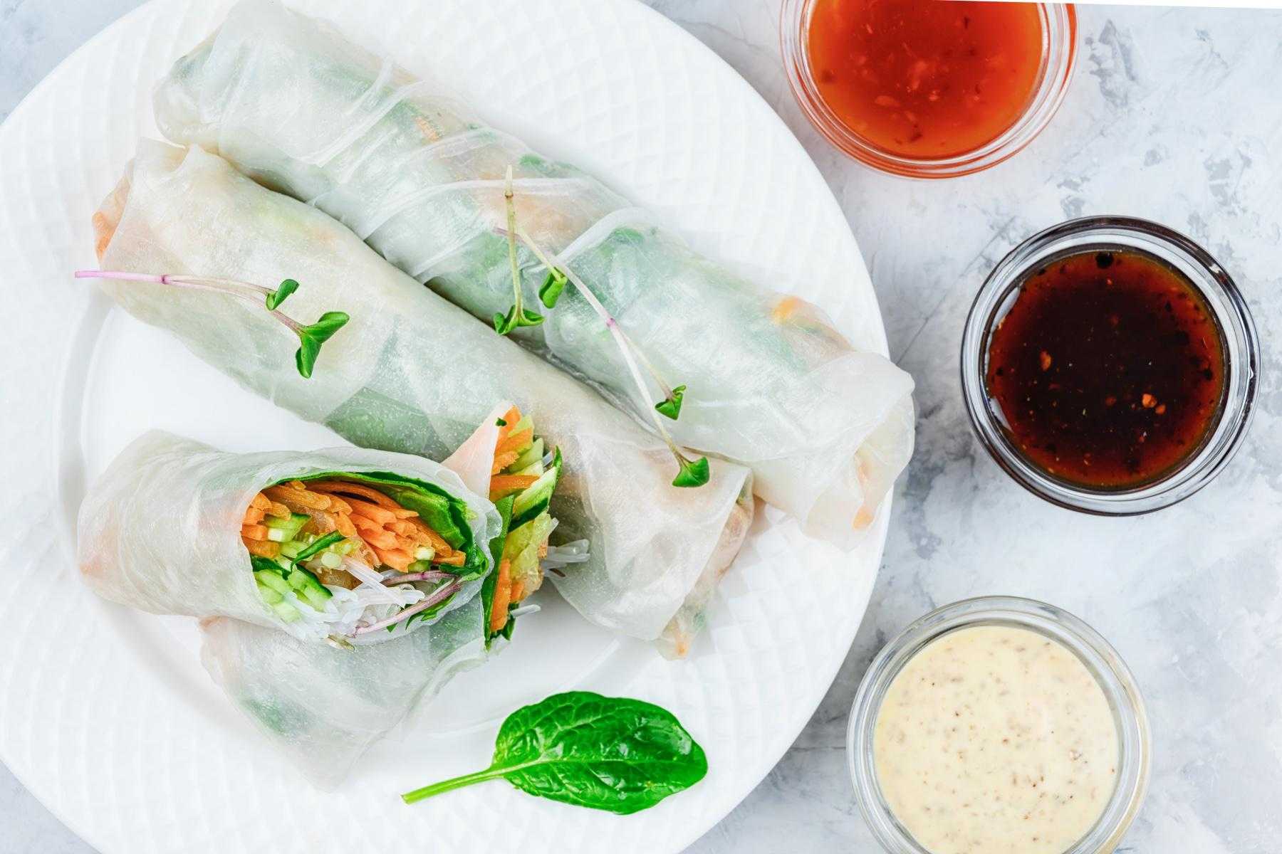 Overhead view of a plate of spring rolls with dipping sauces.