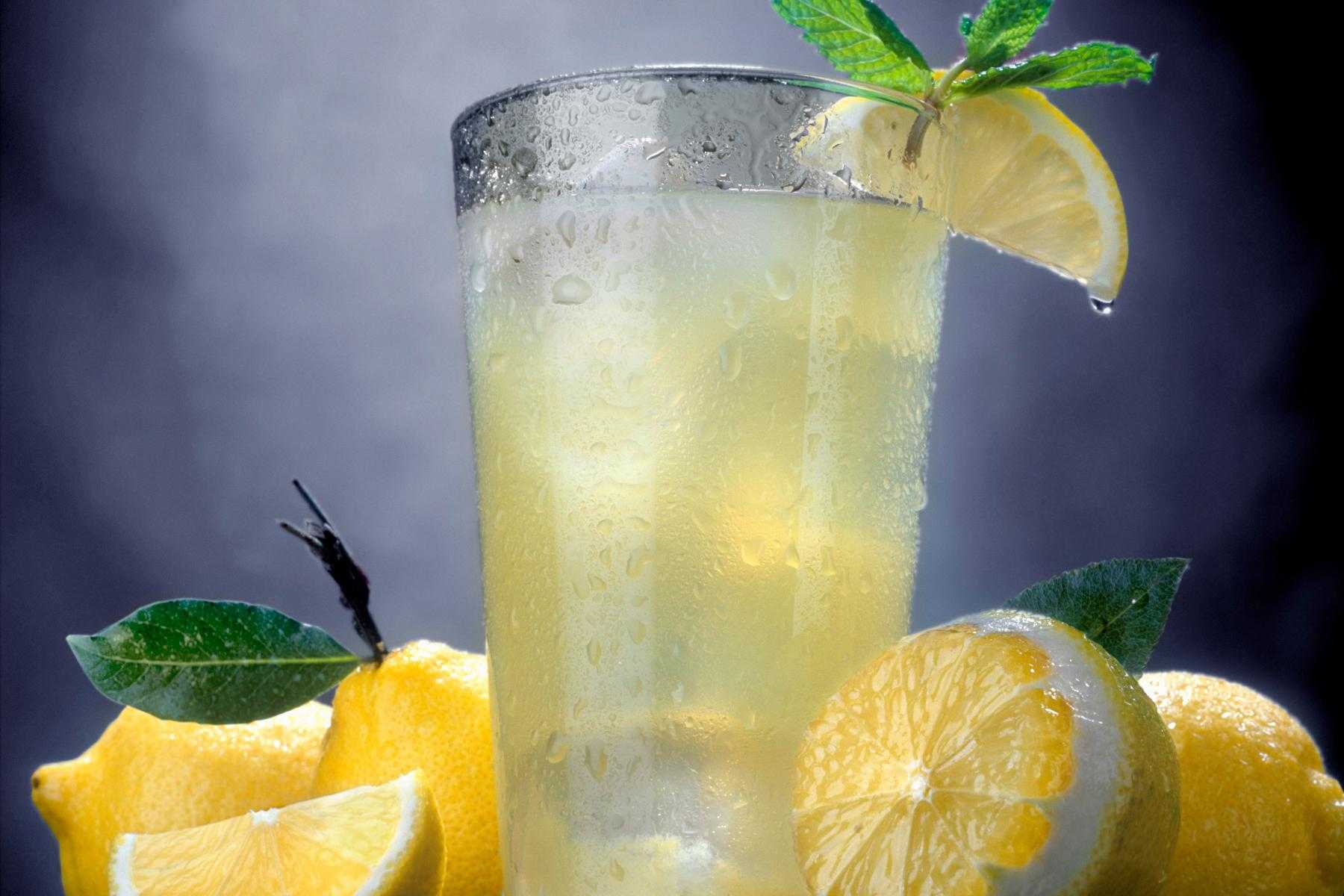 Close-up of glass of lemonade with cut lemons surrounding it.
