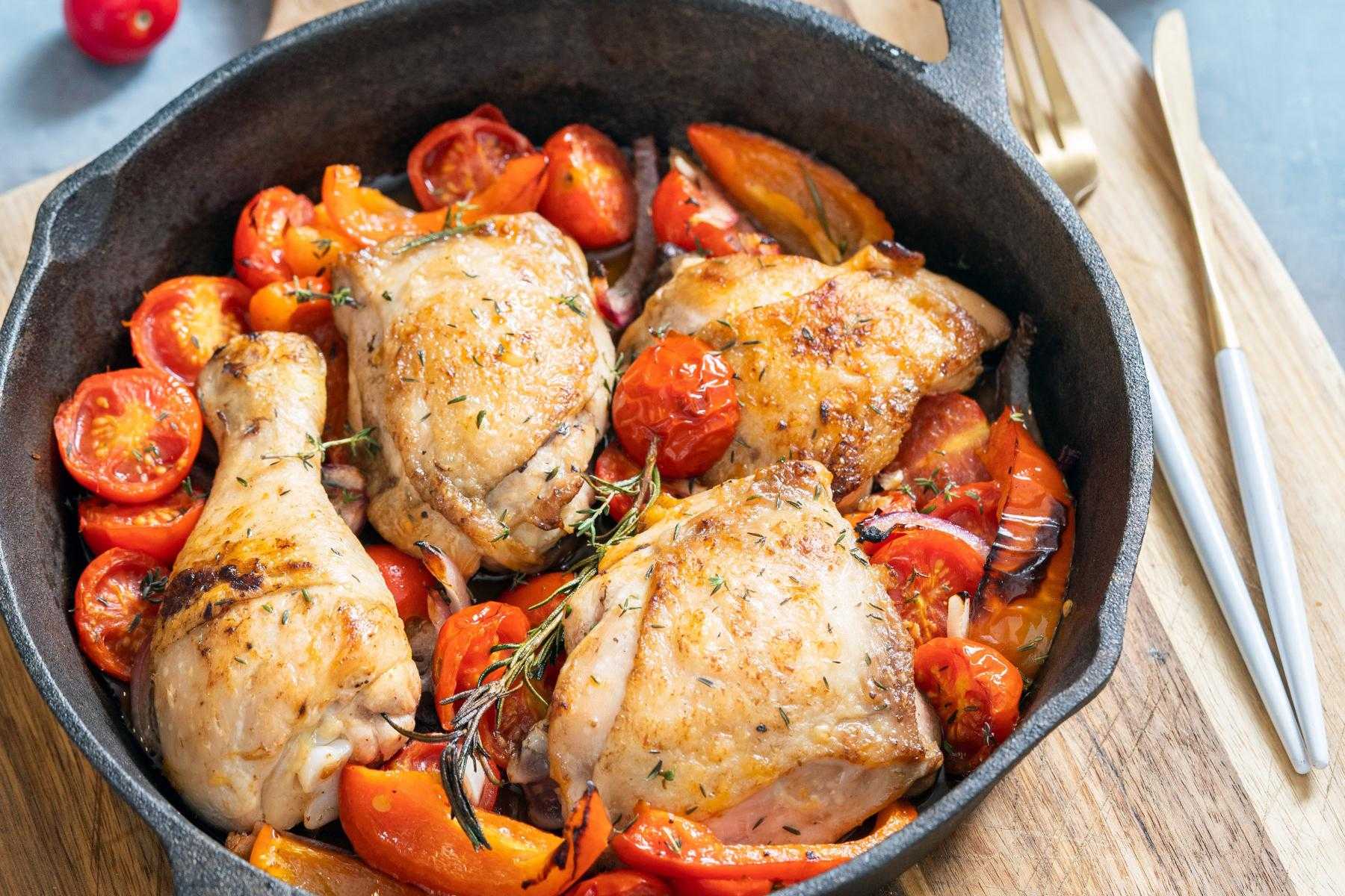 A pan of parmesan-crusted chicken with tomato asparagus sauce.
