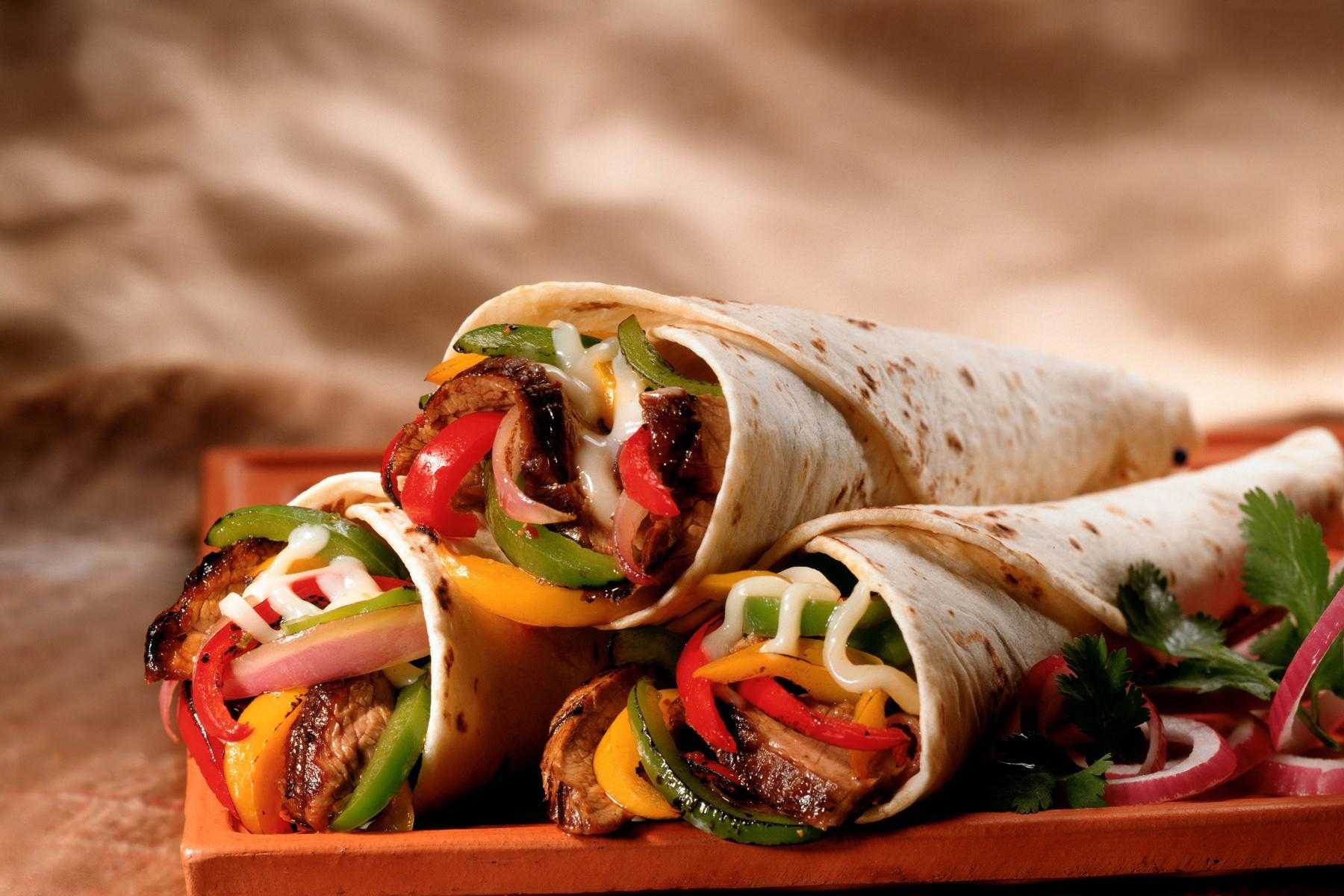 Close-up of steak fajitas on red plate.
