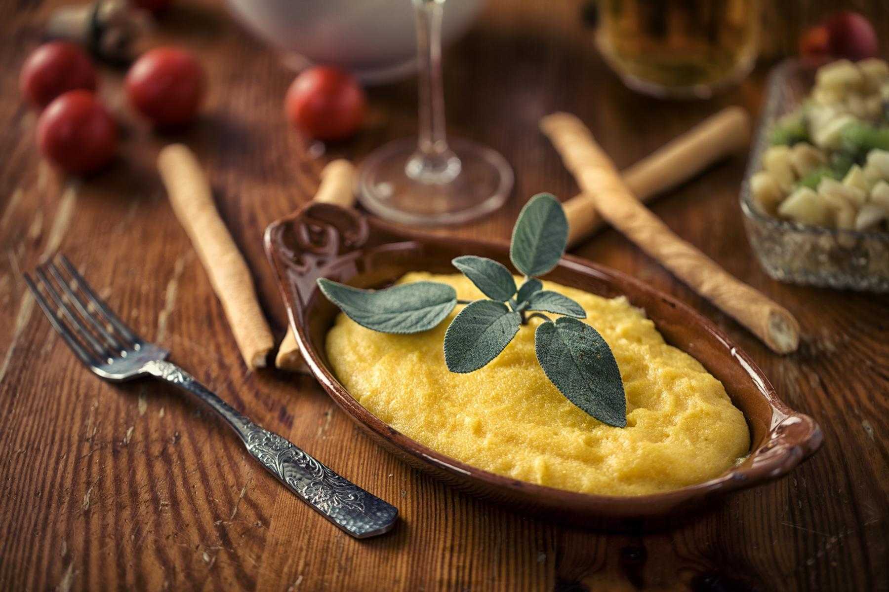 Dish of polenta on dark wood table.
