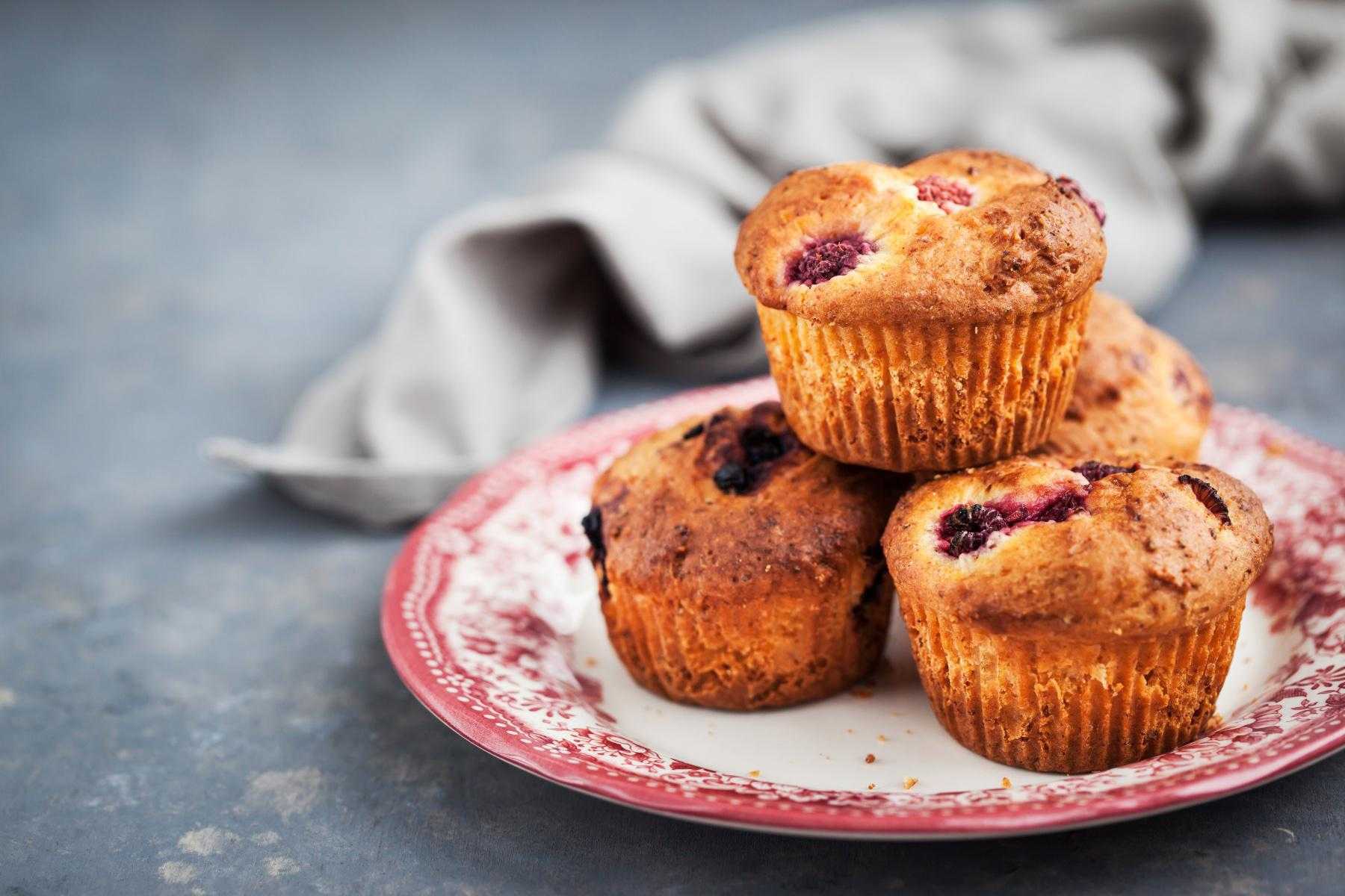 A plate with a stack of lemon raspberry muffins on it.