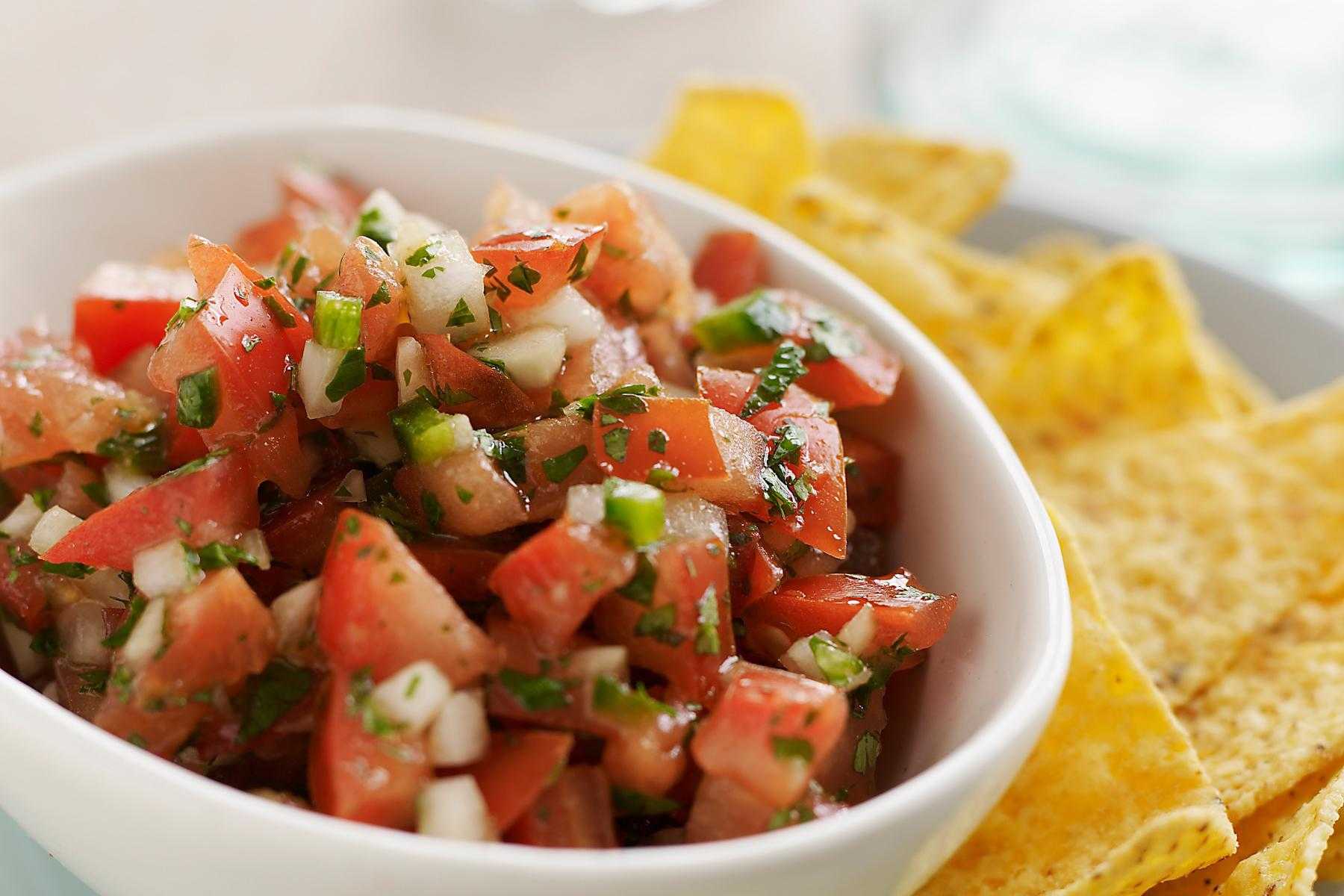 Bowl of pico de Gallo with chips on the side.