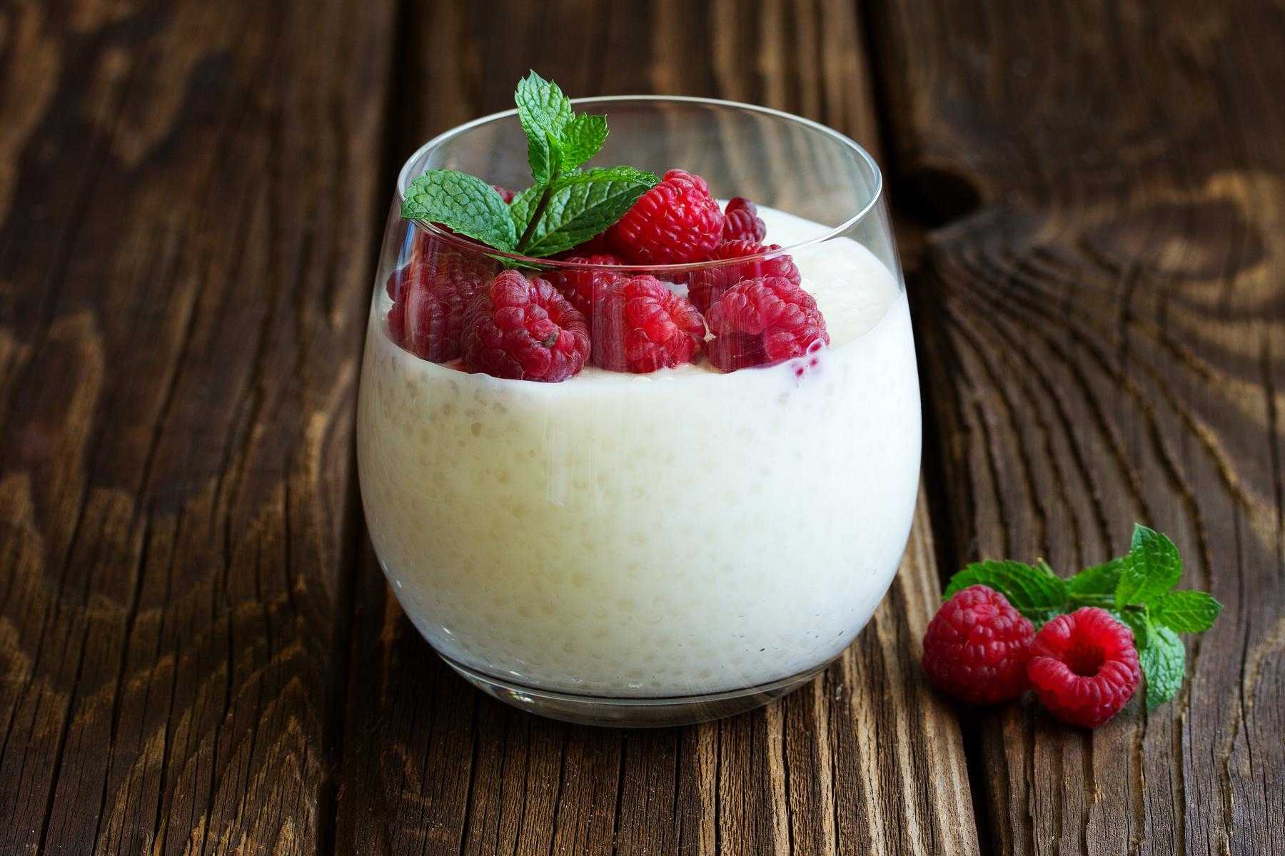 A glass of tapioca pudding with raspberries.