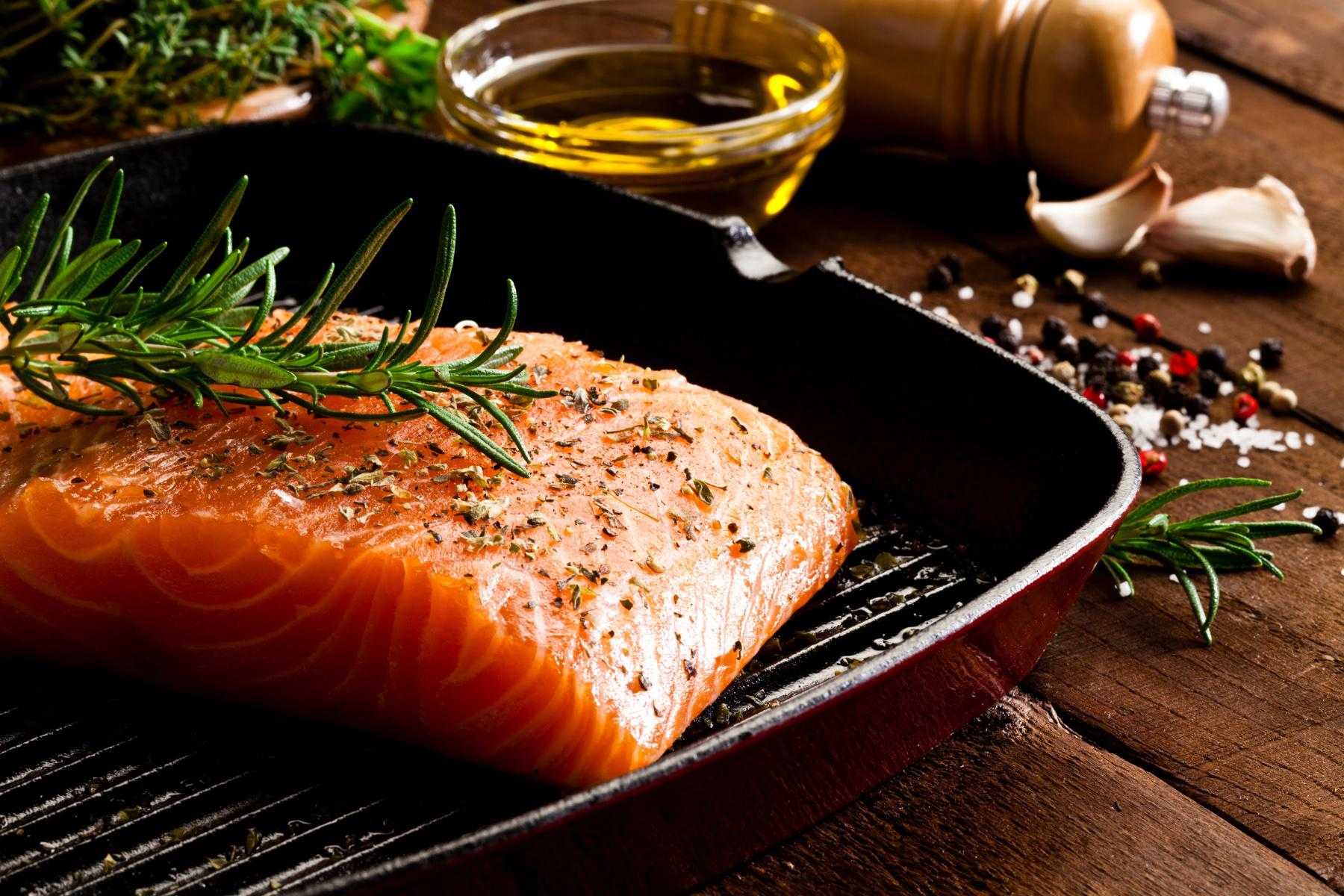 Close-up of a piece of salmon with herbs on top.