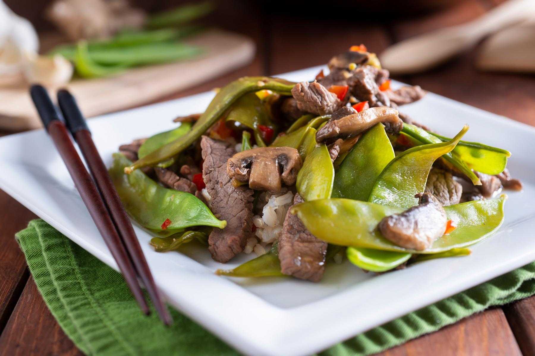 Square plate with sesame beef and snow peas.