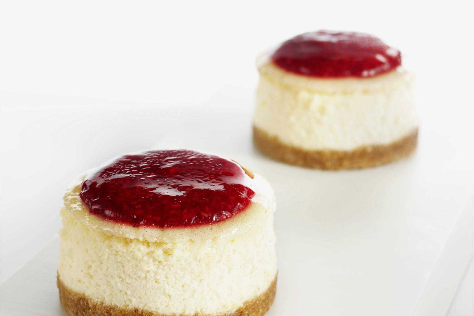 Mini lime cheesecake on plate with strawberry sauce on top.