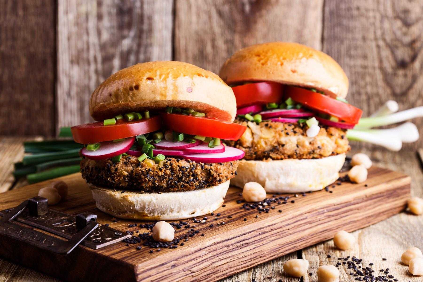 Two mushroom burgers on a wooden plate.