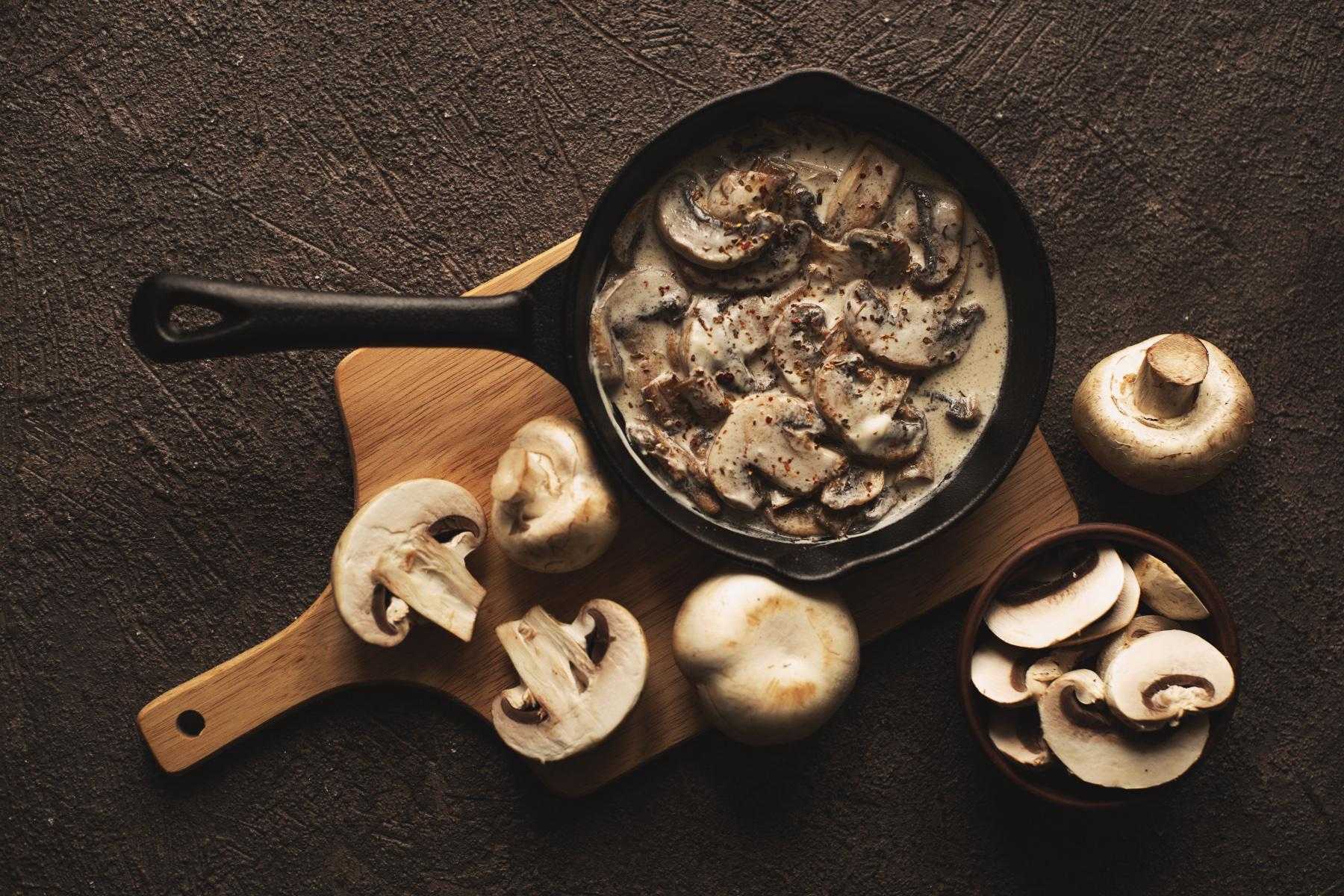 Overhead view of sautéed mushrooms in pan with cream sauce.