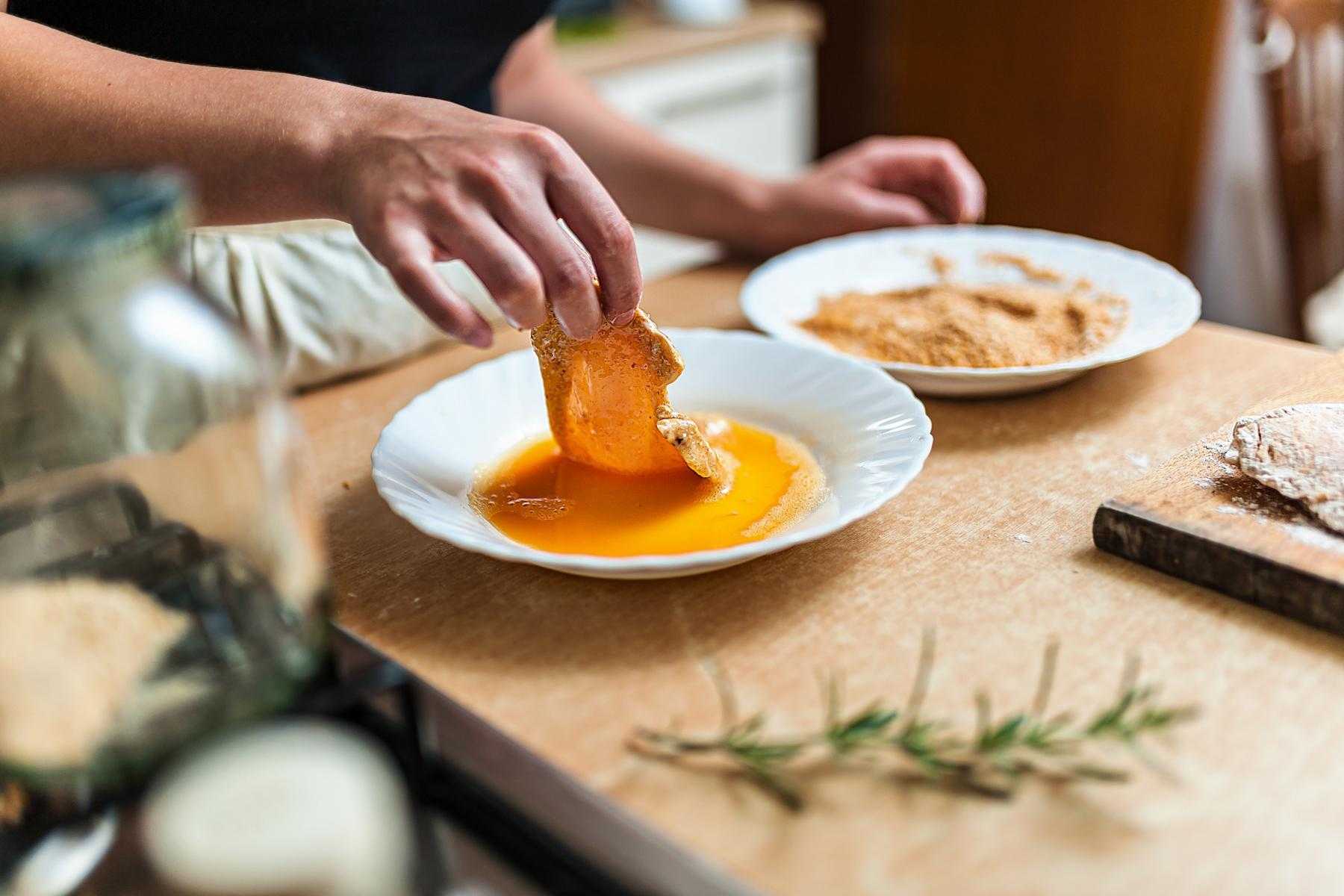 Dipping chicken in egg batter.