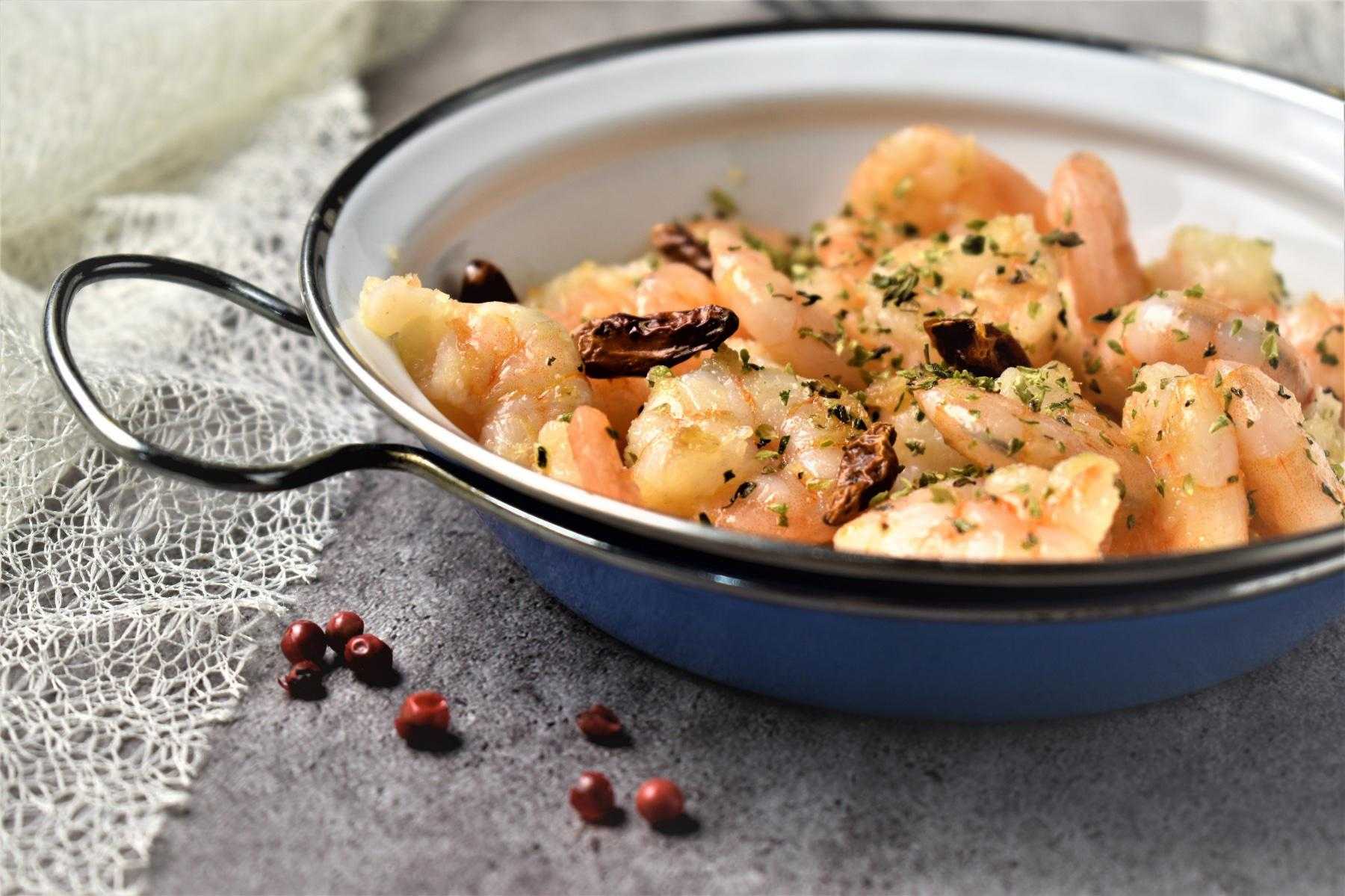 A bowl of shrimp with garlic sauce.