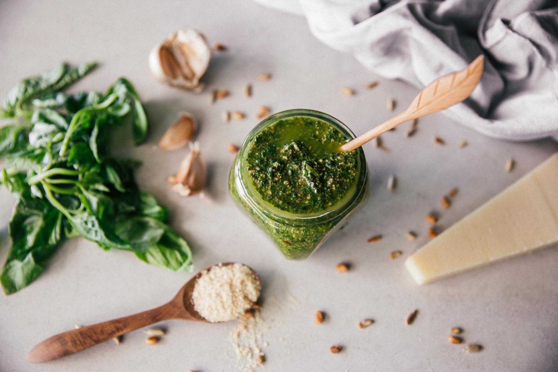 Overhead view of a jar of pesto surrounded by ingredients.