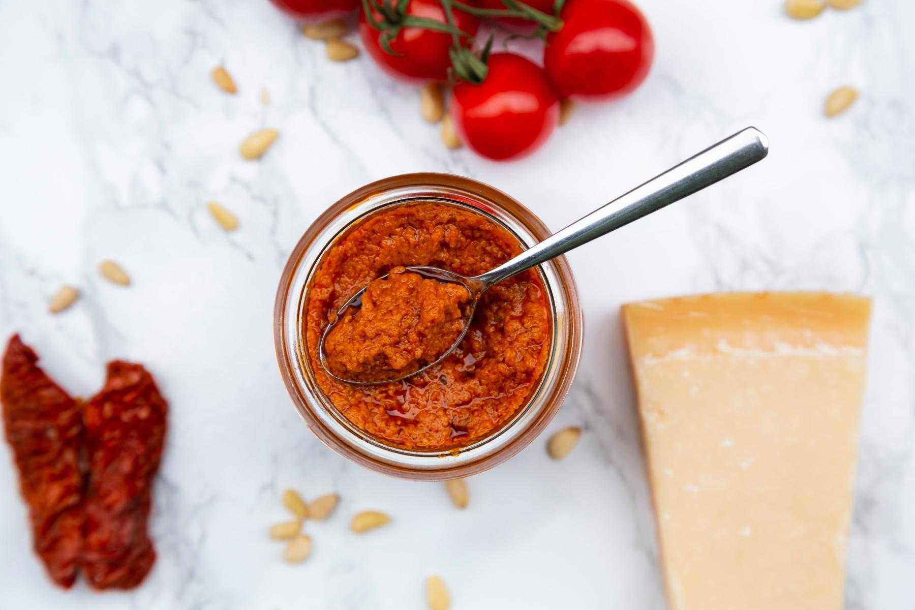 Overhead view of red pepper pesto in glass jar.