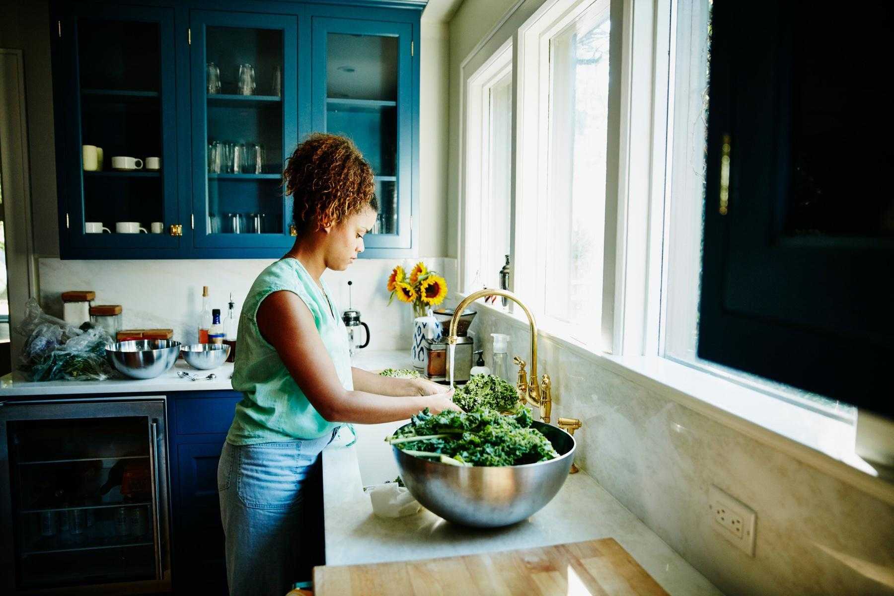 woman washing kale in sink