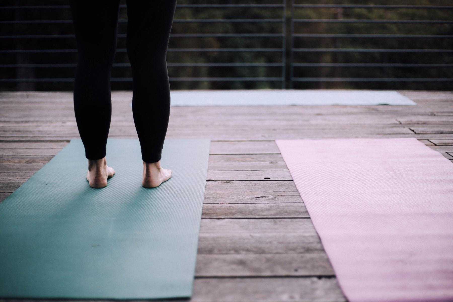 woman's feet standing on yoga mat on deck outside