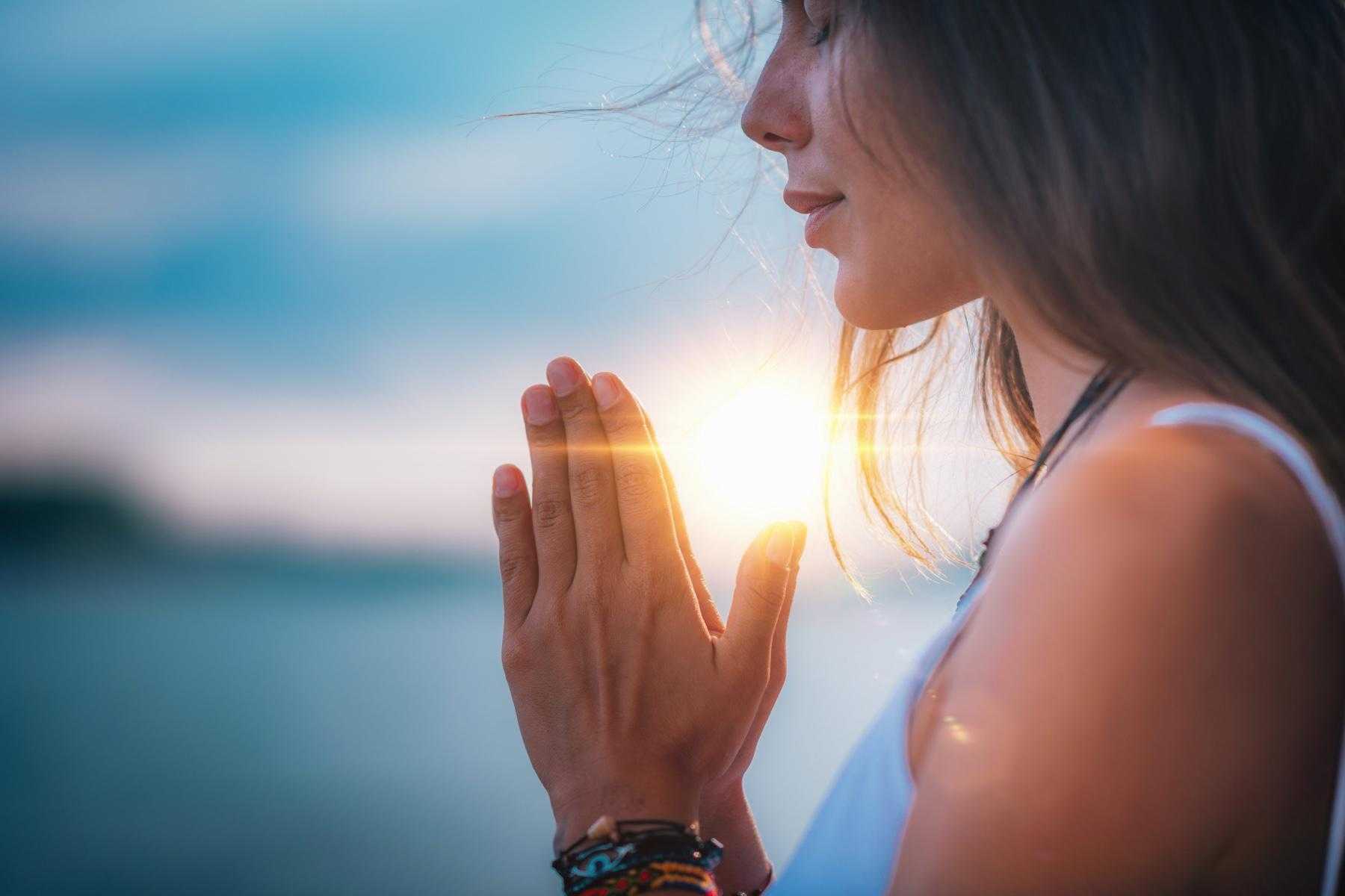 Close up of woman practicing yoga with her hands joined.
